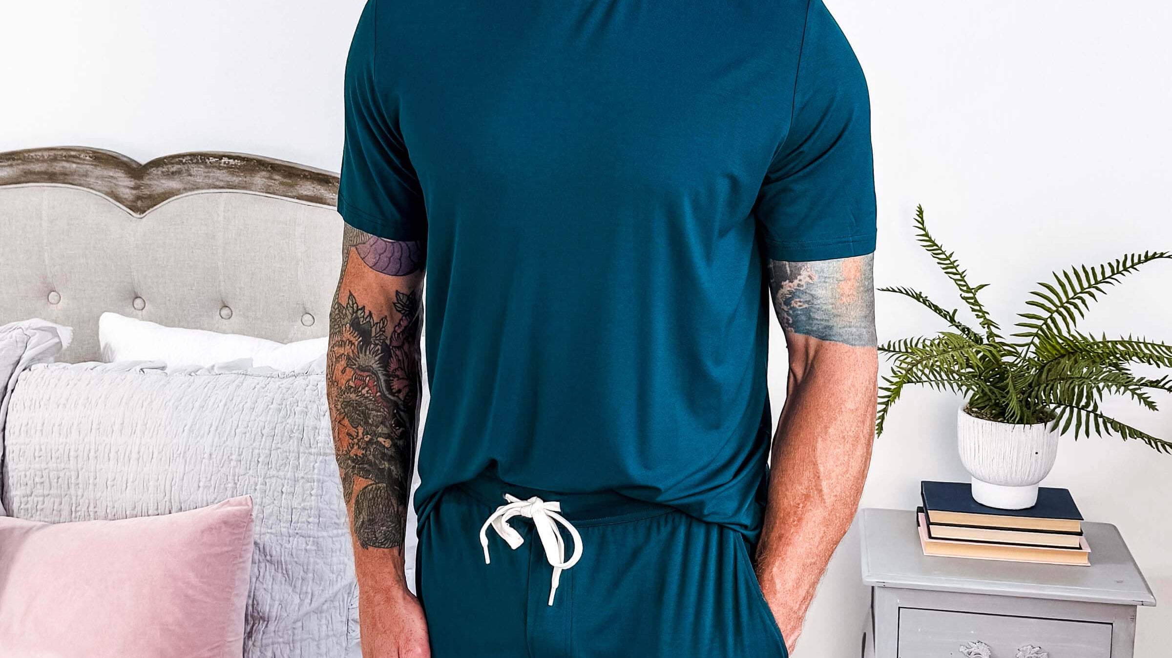 Man in his 40's to 50's wearing a bamboo tee shirt and shorts in a dark teal blue colour. shorts have drawstring and pockets, and shirt is a relaxed crew fit.