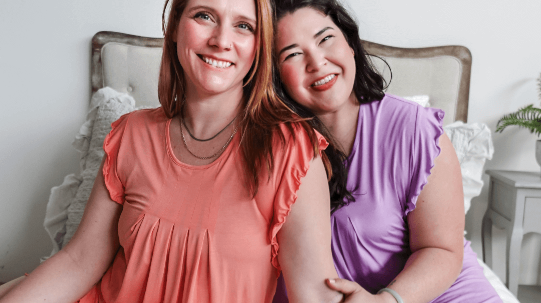 Two women in colorful pajamas smiling together, promoting better sleep with comfortable sleepwear.