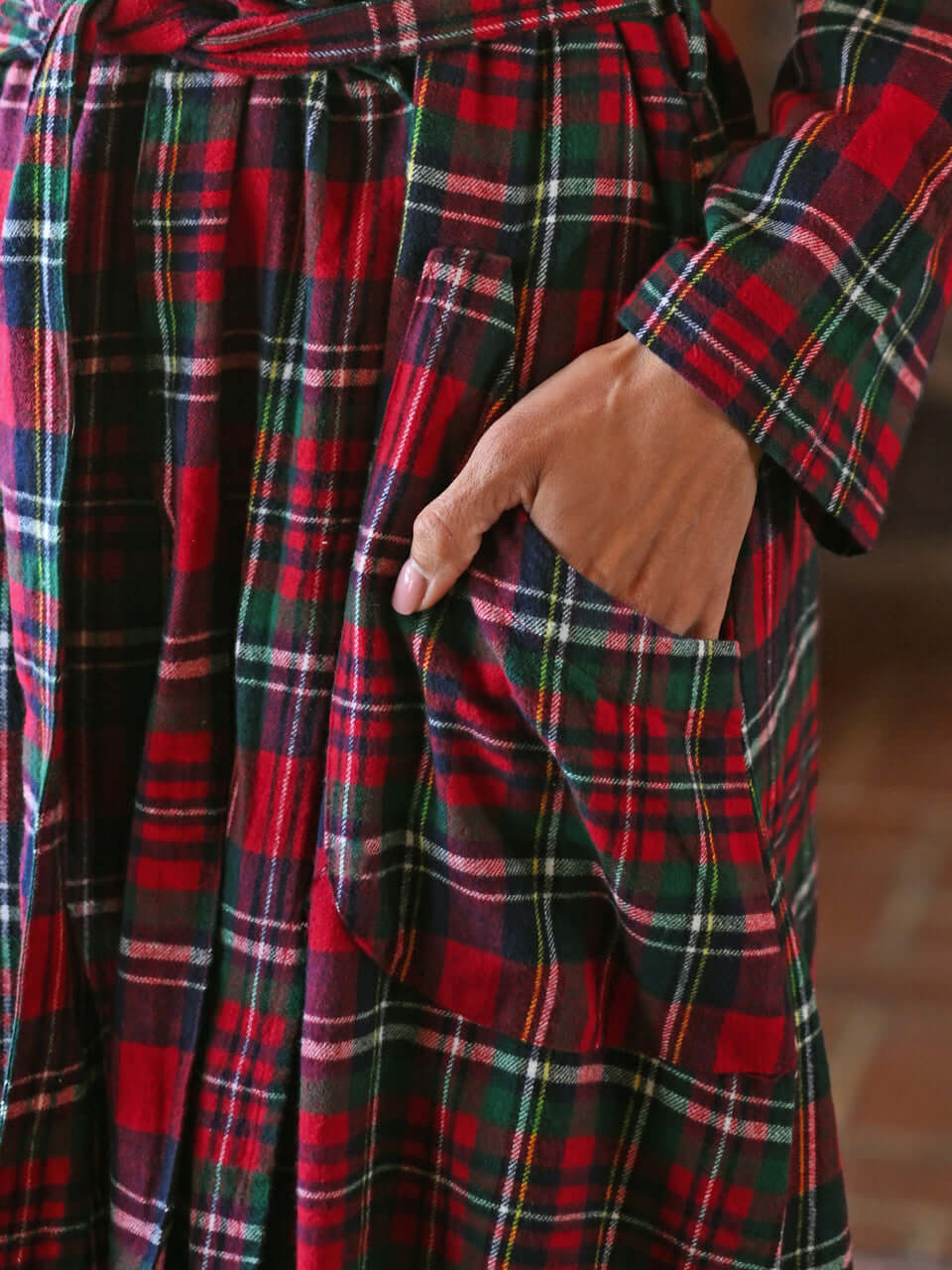 Close-up of the Yuletide Check Dressing Gown featuring red plaid flannel and hand in pocket.