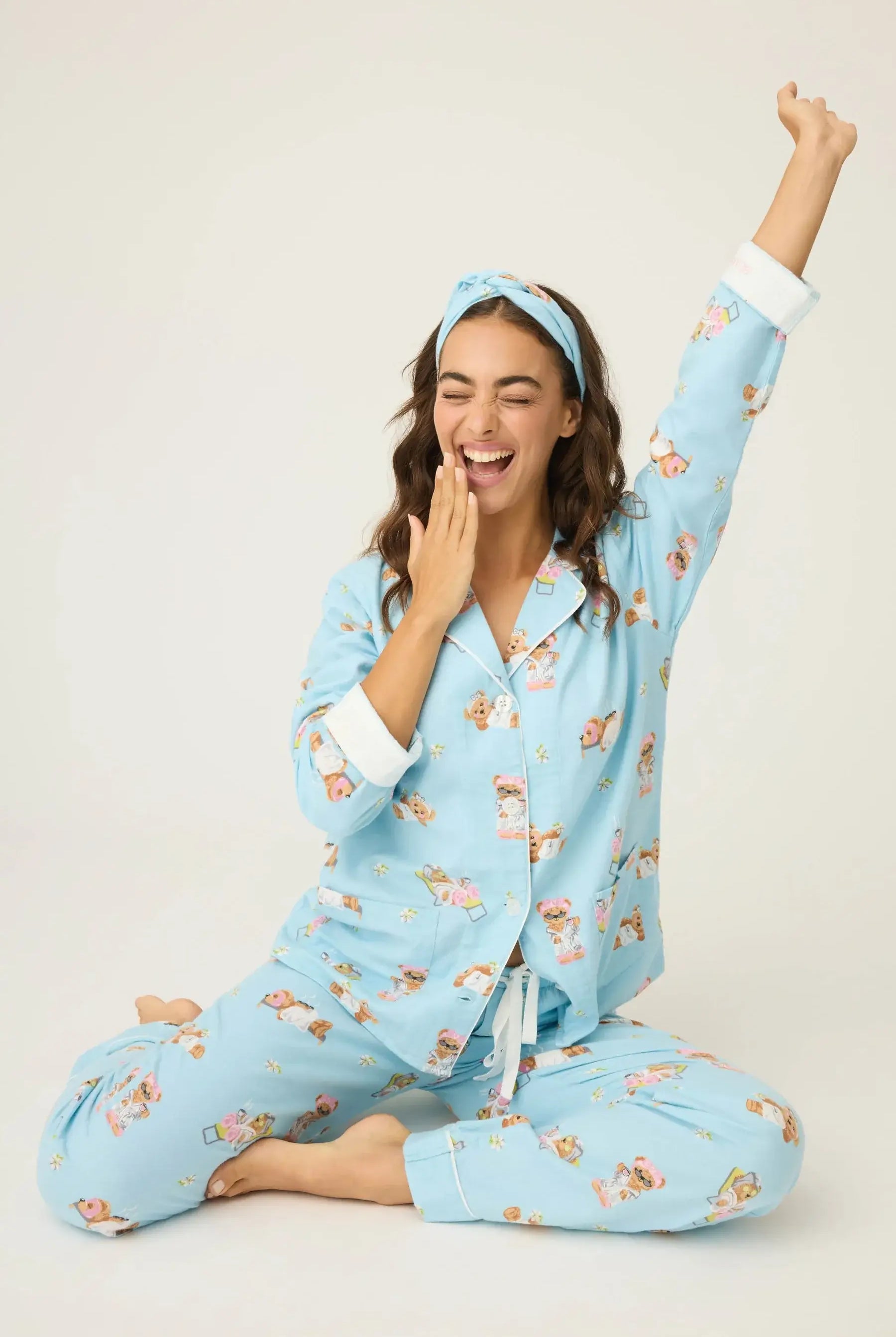 Model wearing Beary Cute Bear Print Flannel PJ Set by PJ SALVAGE, smiling and relaxing in light blue pajamas.
