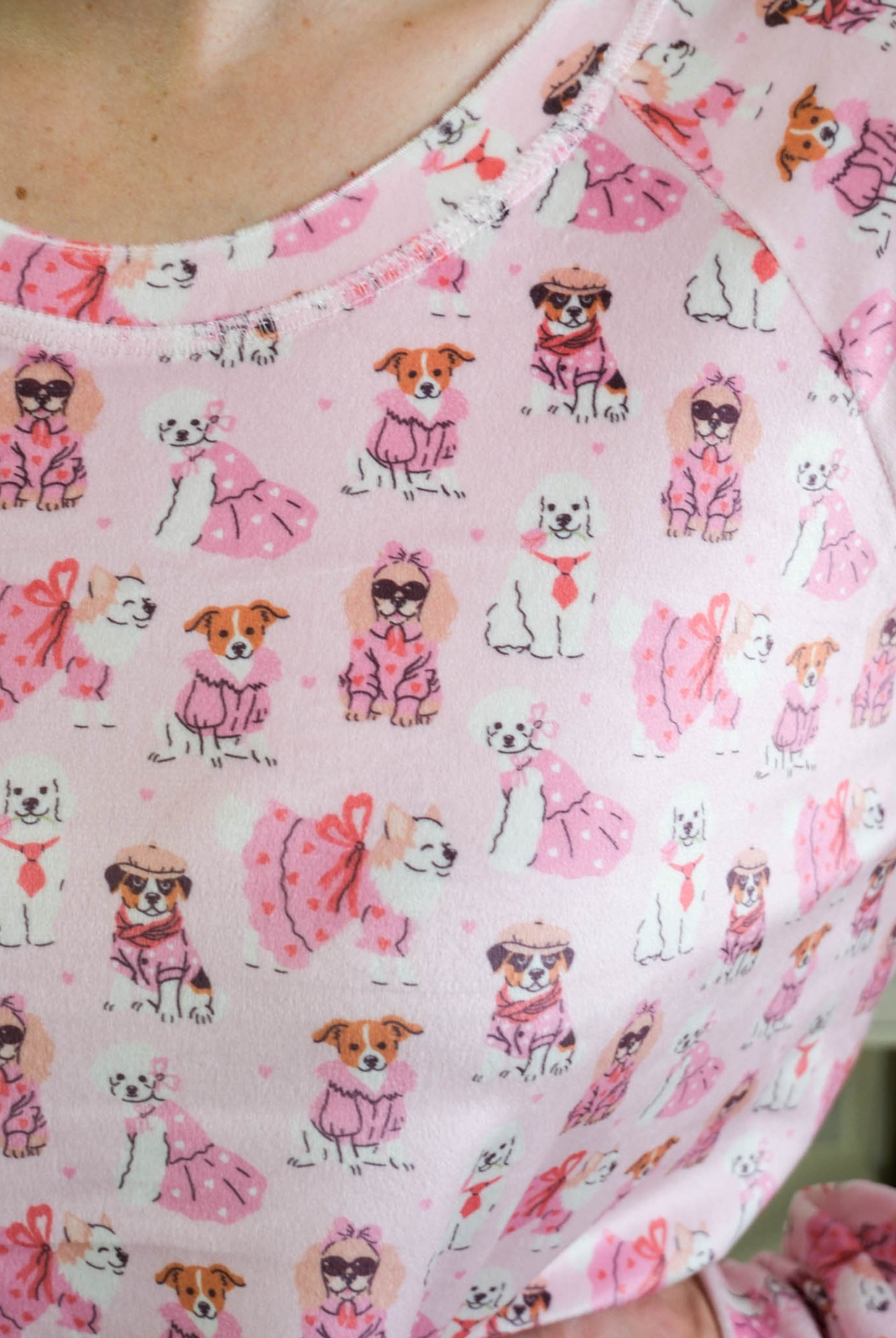 Close up of person wearing Miranda Nic women's pink velour long sleeve top and jogger pants loungewear set featuring Chic Puppies dog print showing print and texture