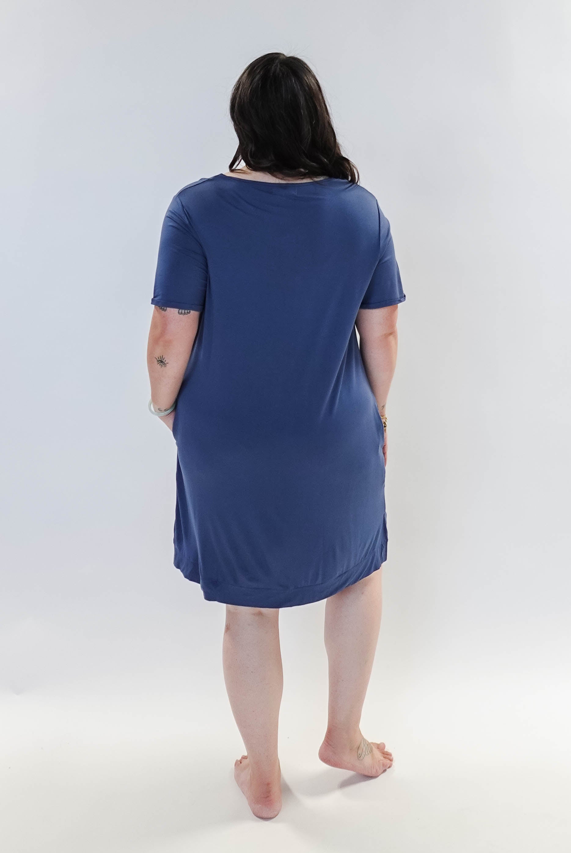 Stylish model wearing Denim Blue V Neck Bamboo Nightshirt dress with pockets, showcasing versatility in sleepwear and everyday fashion. Showing back view