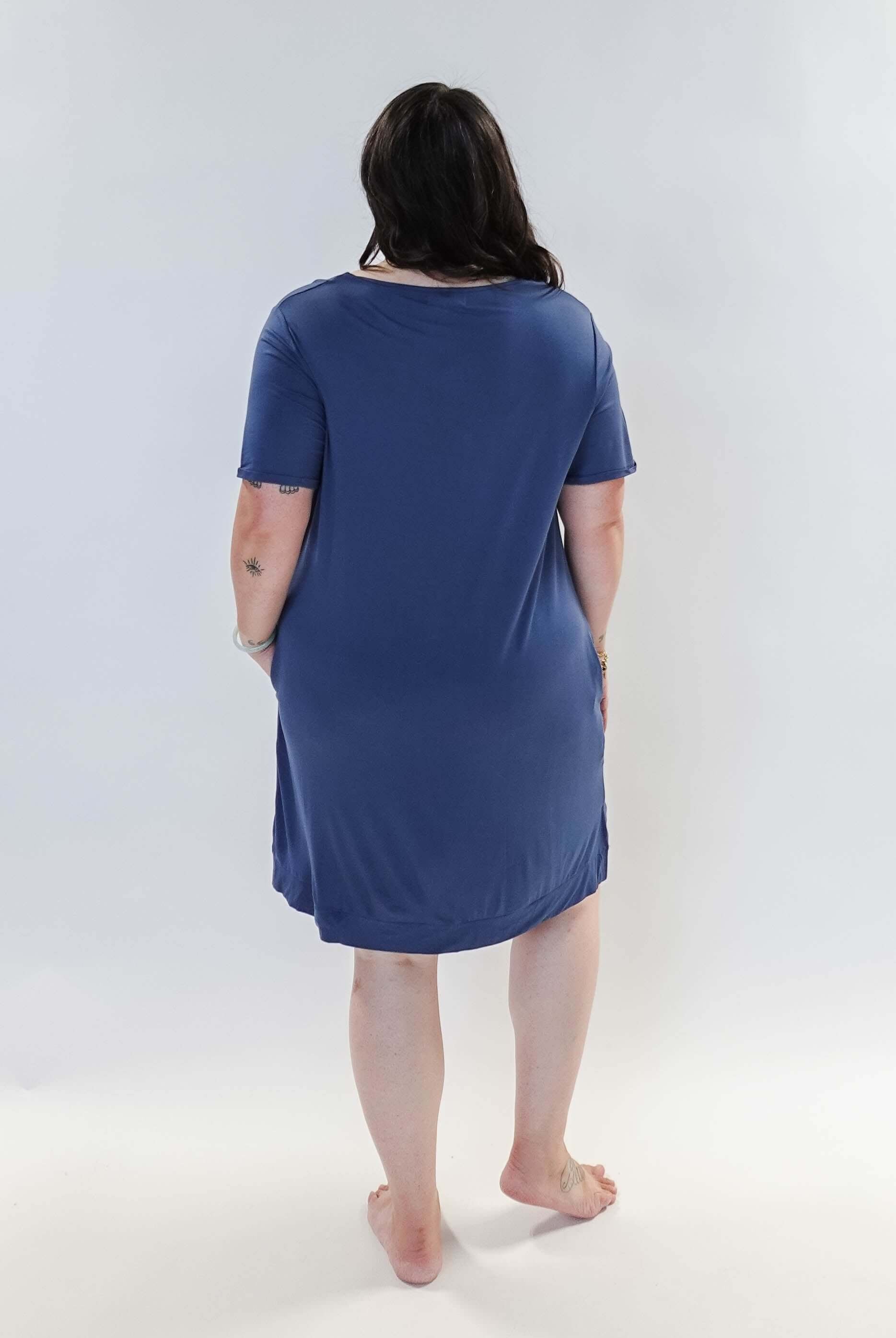 Stylish model wearing Denim Blue V Neck Bamboo Nightshirt dress with pockets, showcasing versatility in sleepwear and everyday fashion. Showing back view