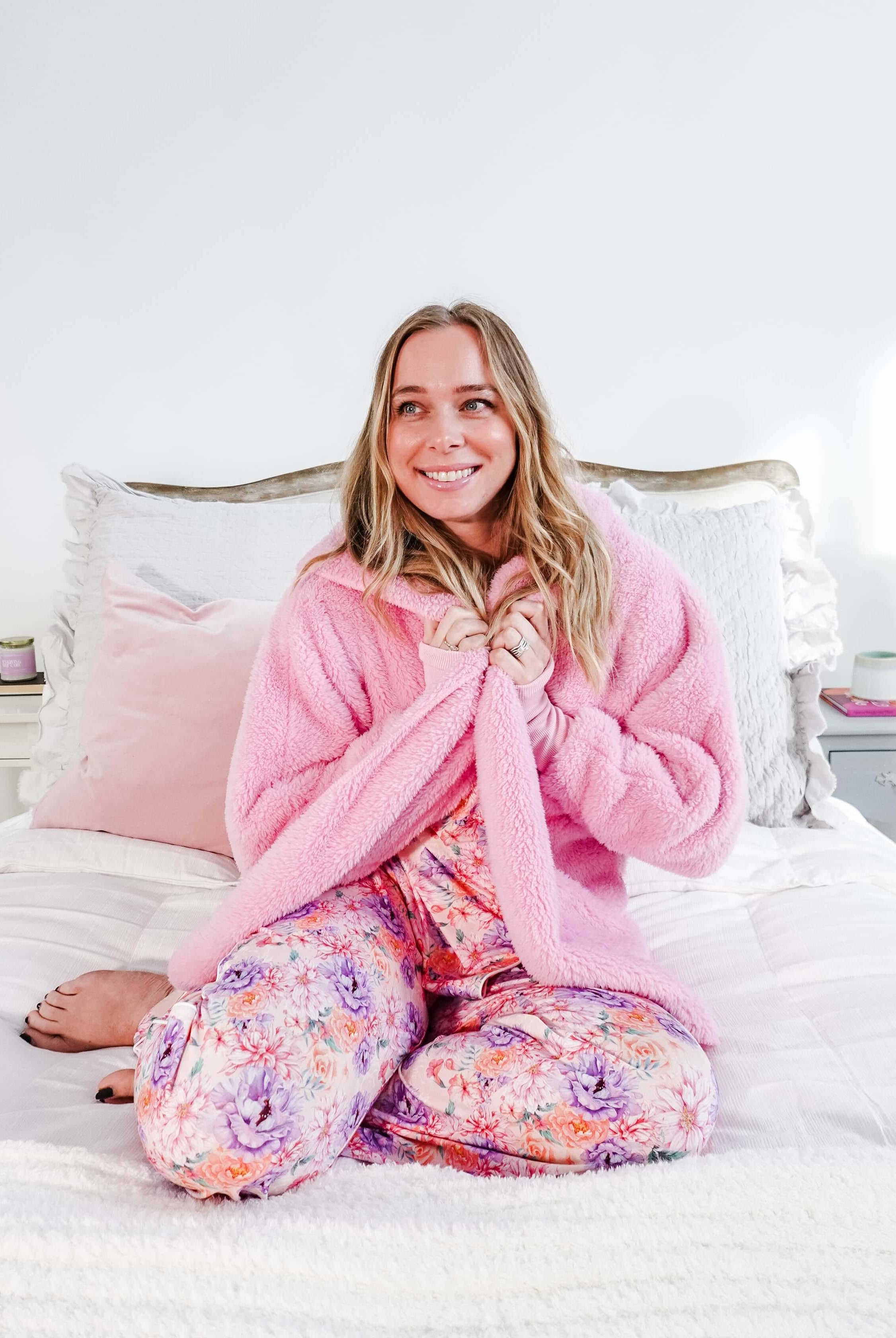 Essential Hooded Fluffy Cozy Cardigan with Pockets worn by a smiling woman sitting on a bed.