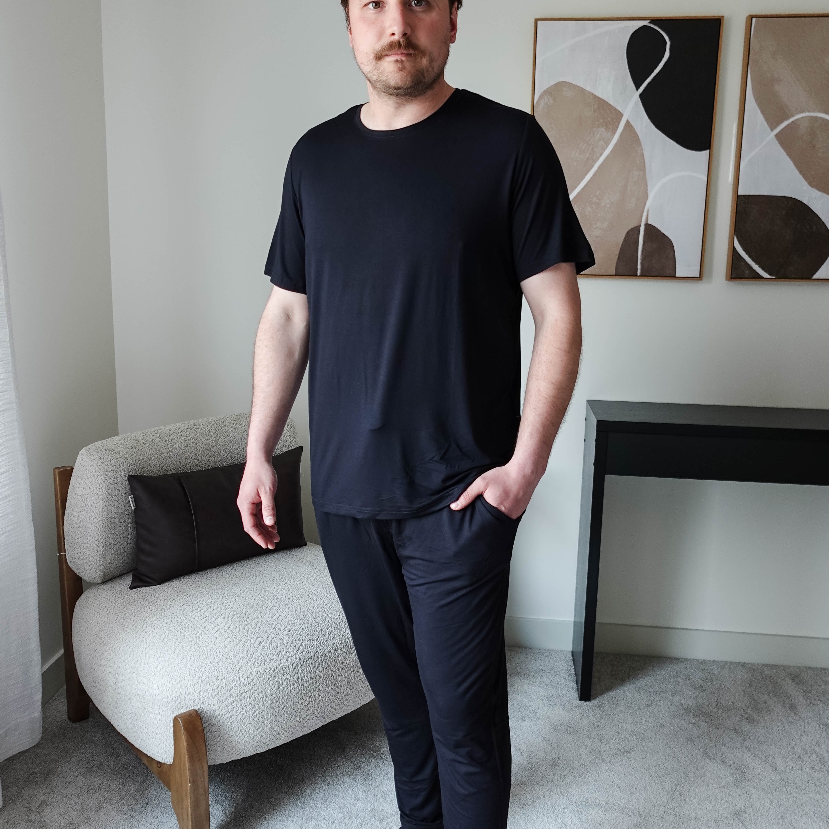 Black Unisex Short Sleeve Tee Bamboo showcased on a model standing in a modern interior setting.