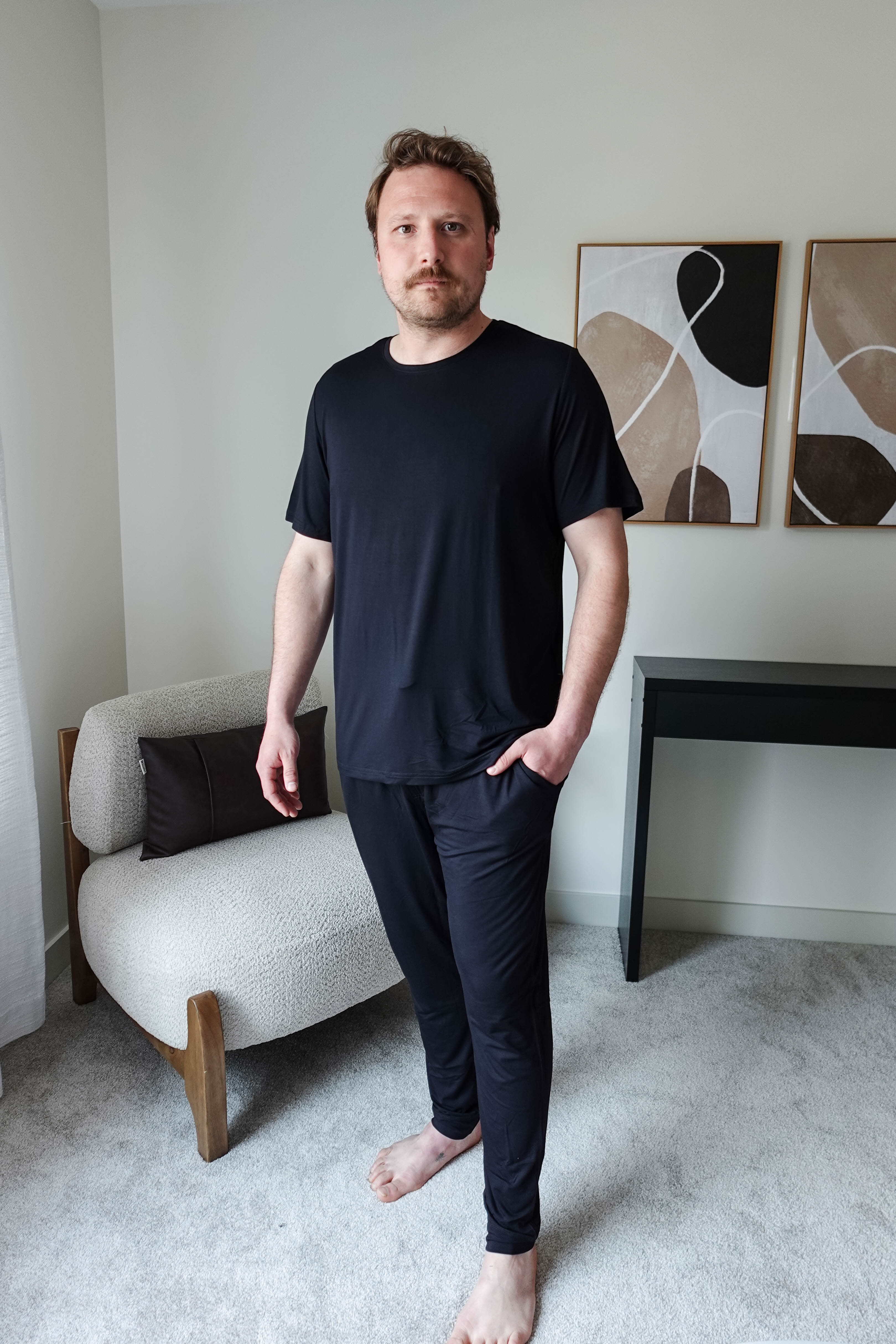 Black Unisex Short Sleeve Tee Bamboo showcased on a model standing in a modern interior setting.