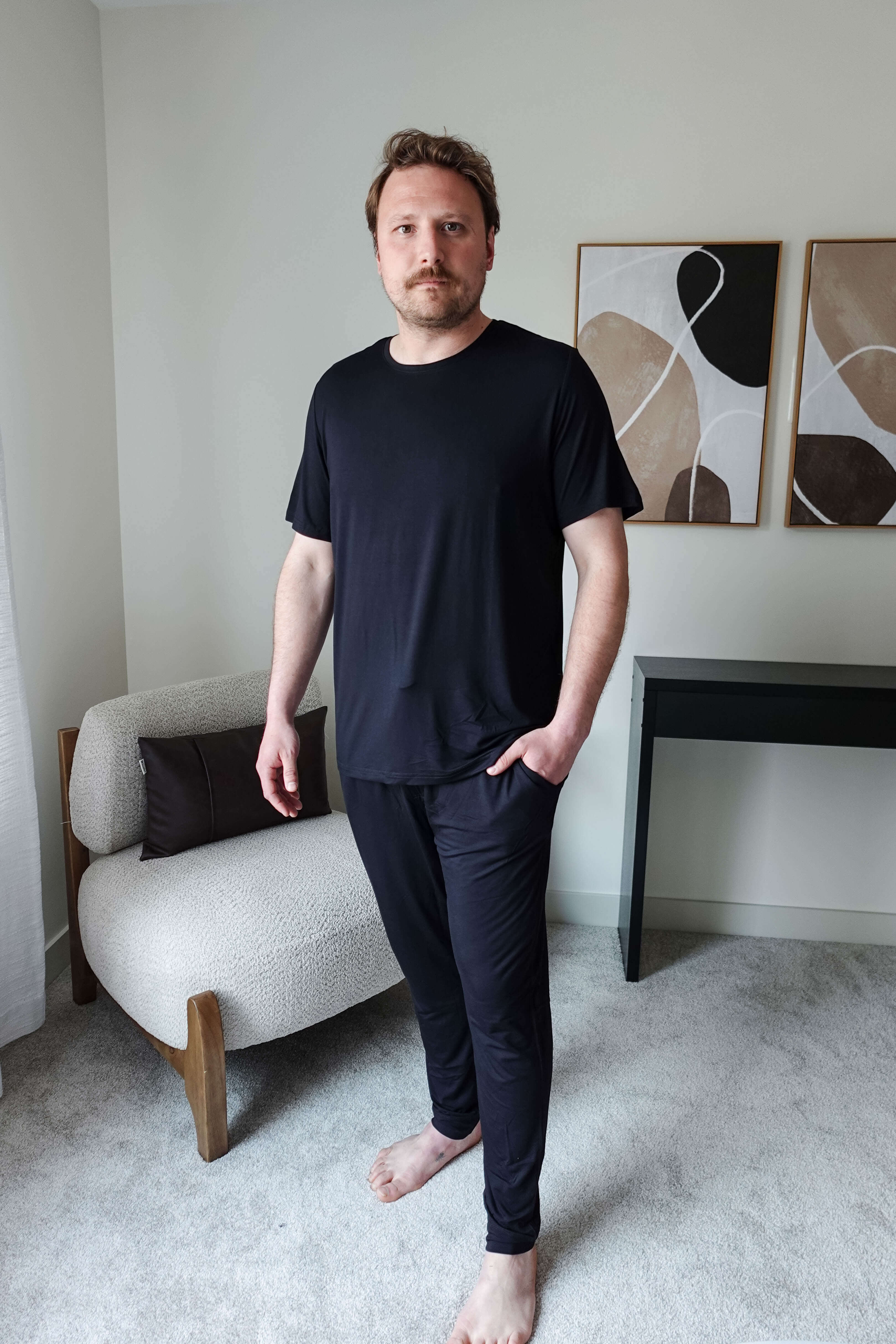 Black Unisex Short Sleeve Tee Bamboo showcased on a model standing in a modern interior setting.