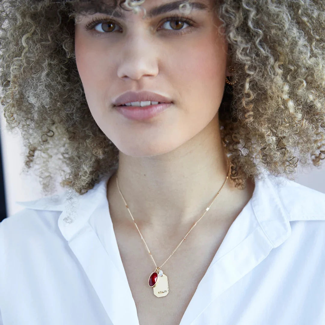 Birthstone Charm Necklace in 14k Plated Gold featuring a ruby stone, labeled 'Vitality', by Foxy Originals. Birthstone Charm Necklace in 14k Plated Gold for JUNE featuring a ruby stone, labeled 'Vitality', by Foxy Originals.