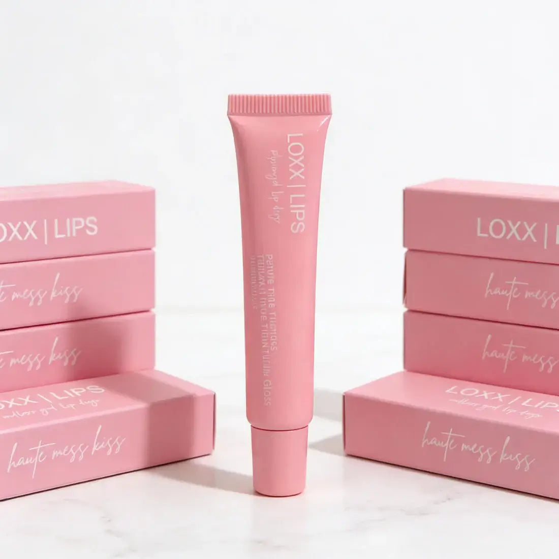 LOXX LIPS Peptide Lip Gloss Haute Mess Kiss Pink Tint packaging displayed, featuring a tube in front of pink boxes.