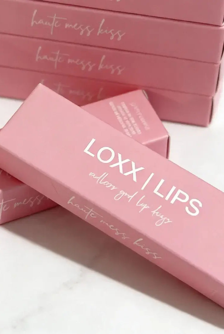 LOXX LIPS Peptide Lip Gloss Haute Mess Kiss Pink Tint packaging displayed on a marble surface.