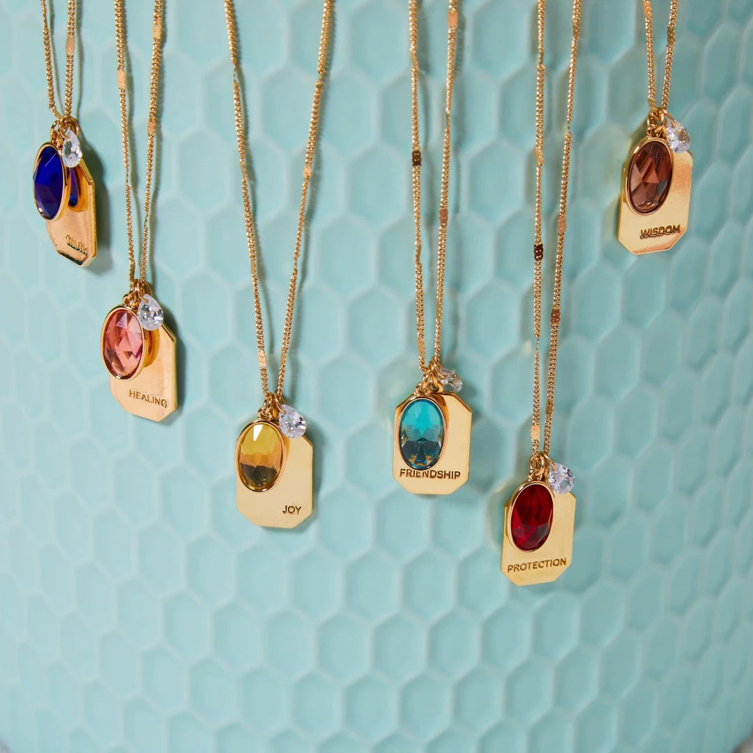 all-groups Birthstone Charm Necklace in 14k Plated Gold with oval-cut stones and intention words displayed on a blue background.
