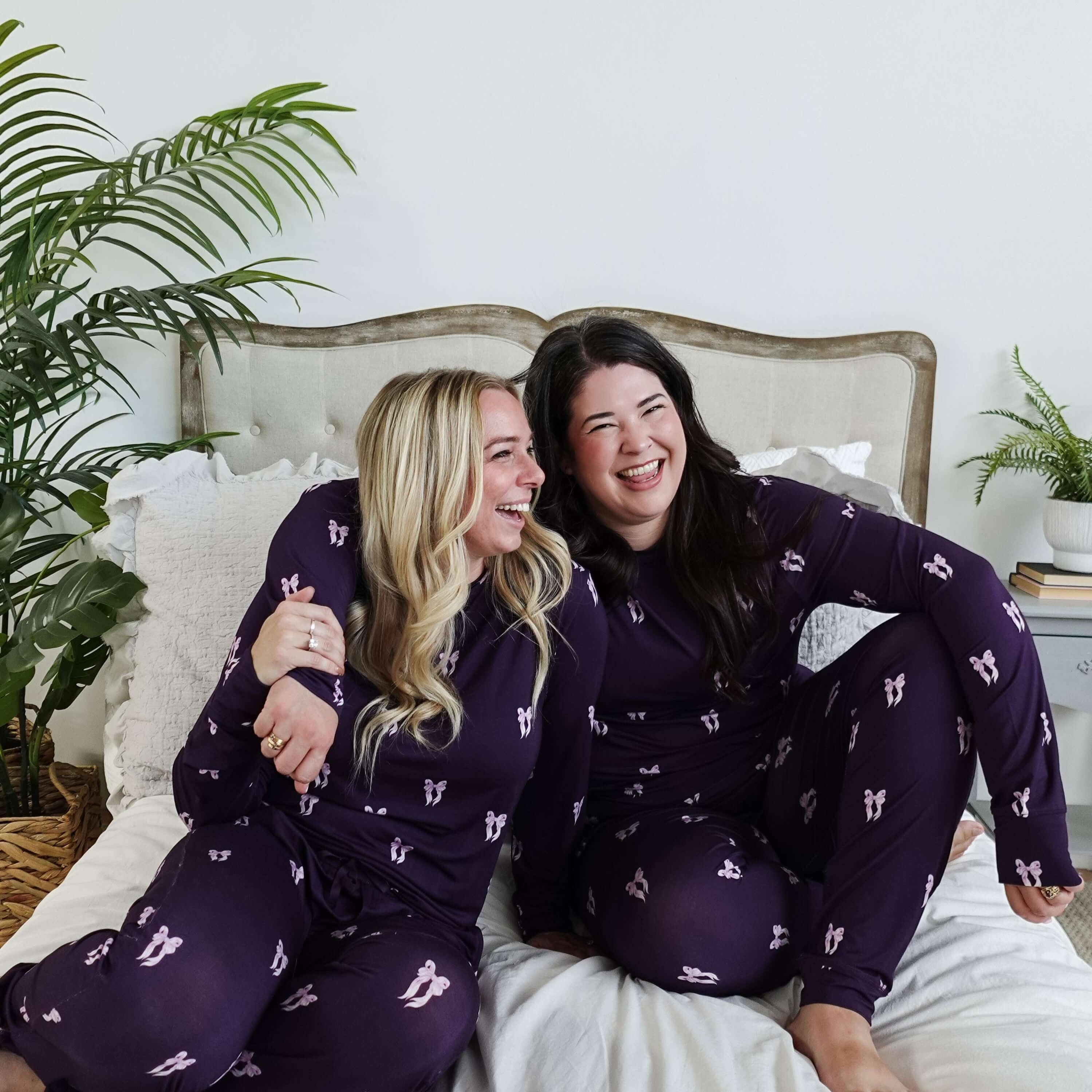 Purple Bows Print Long Sleeve & Jogger Bamboo PJ Set by Georgia Rylan, two models laughing on a plush bed showcasing the pyjama set