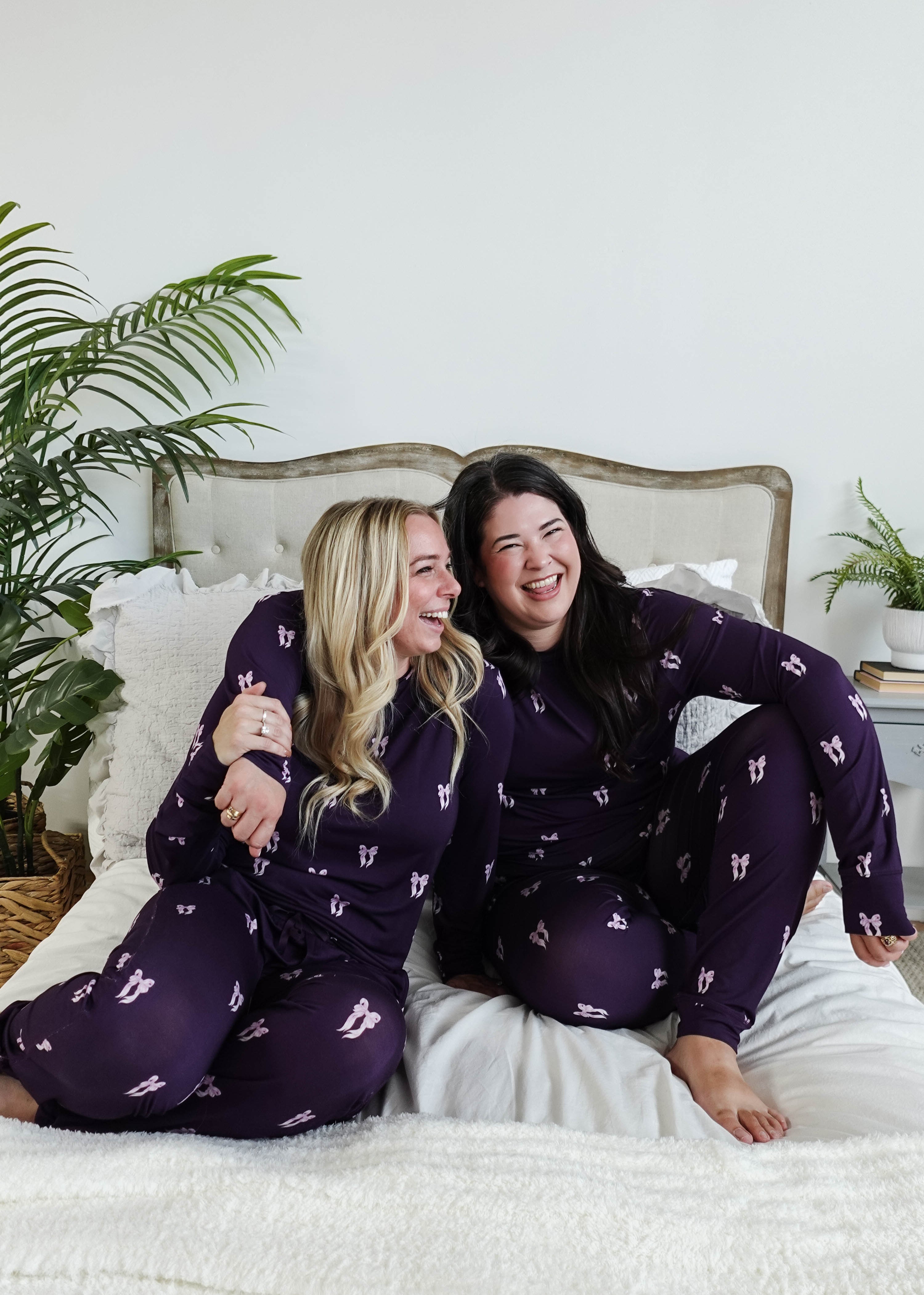 Purple Bows Print Long Sleeve & Jogger Bamboo PJ Set by Georgia Rylan, two models laughing on a plush bed showcasing the pyjama set