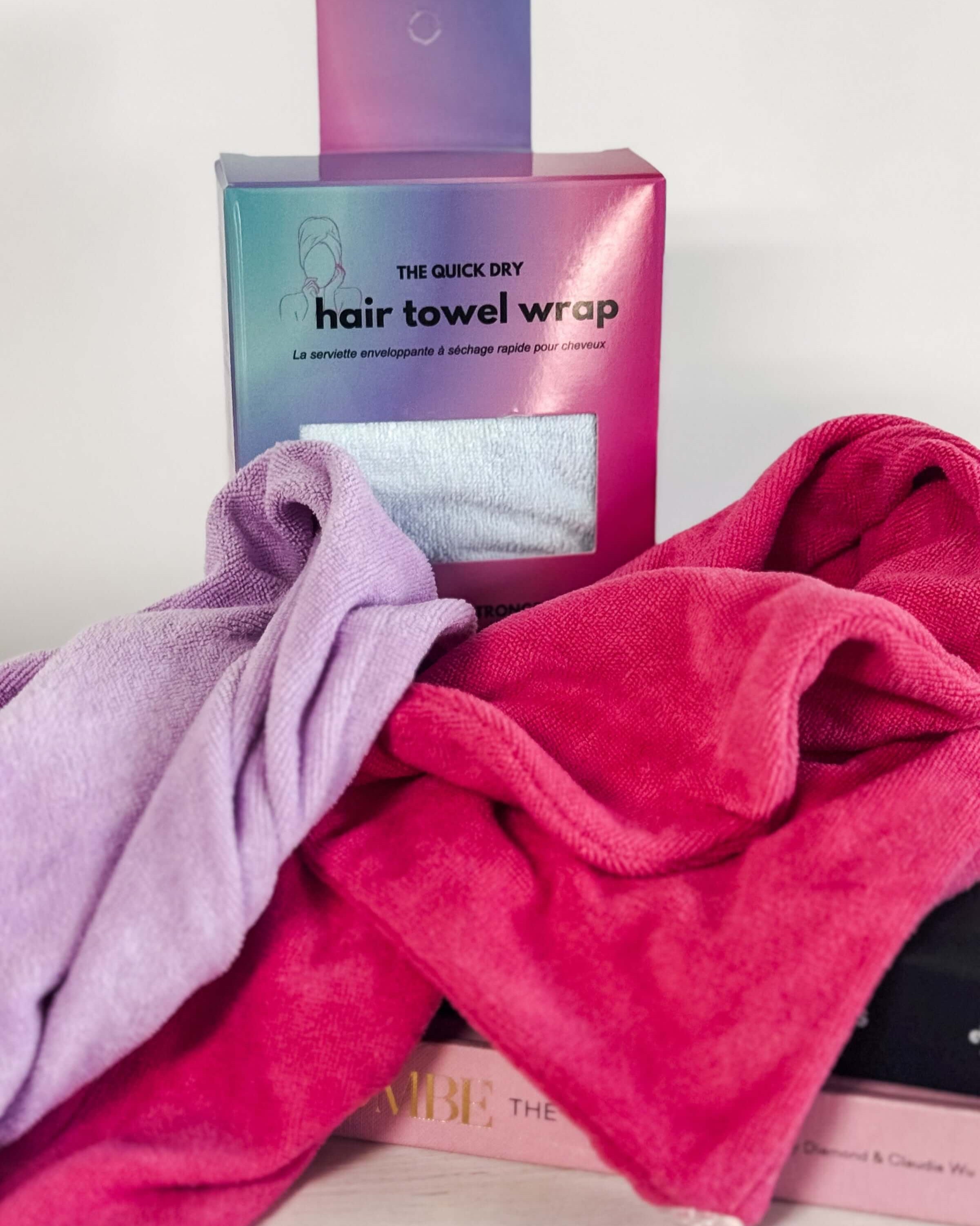 Pink and purple hair towel wraps with packaging on a white surface