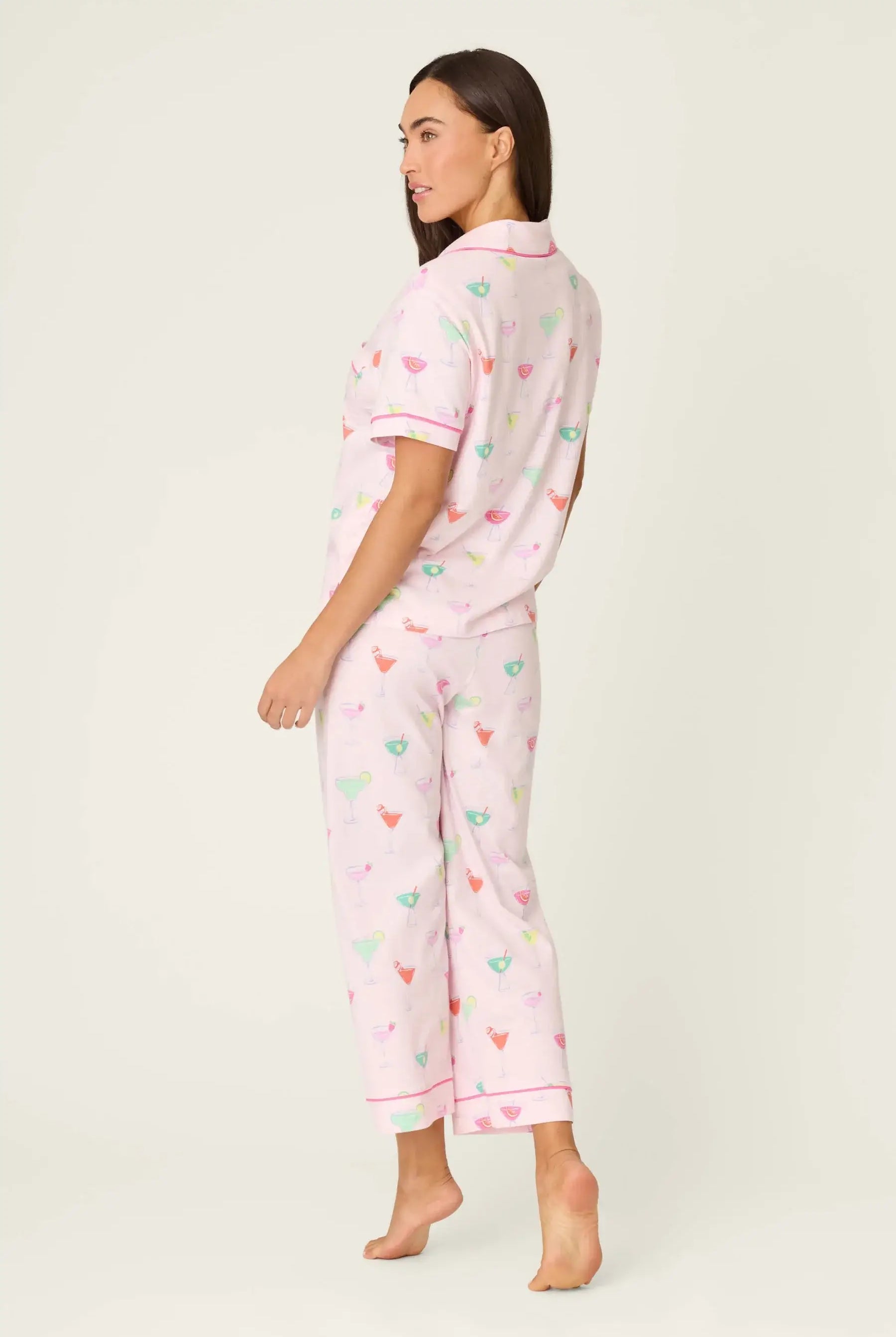PJ SALVAGE Whimsy Cropped PJ Set in Light Pink Sip Happens print showing cocktail glasses in various colours. Model stands wearing the set against a light background showing the full length from the back of the set
