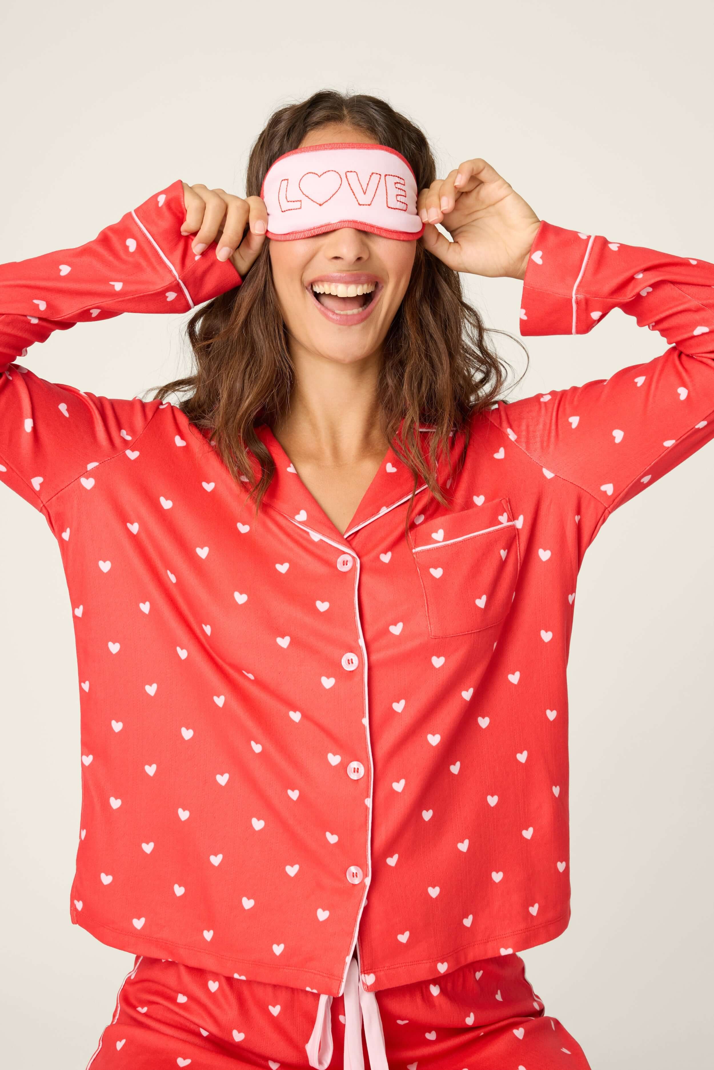 Model wearing Red Hearts Pointelle Button Up Pajama Gift Set with eyemask, smiling and enjoying comfort in stylish loungewear.