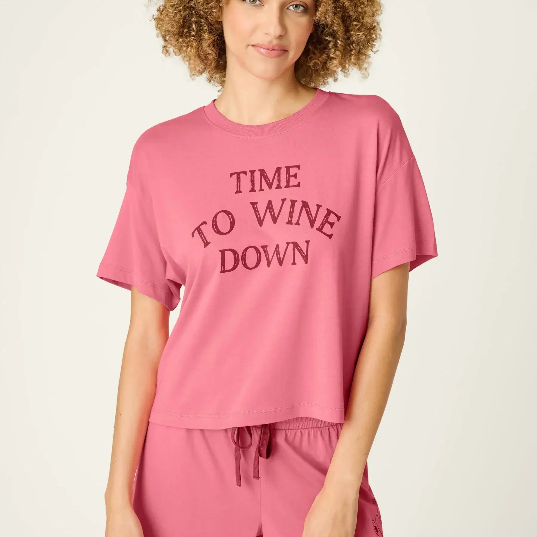 PJ SALVAGE Graphic Print Softee Tee & Short Lounge Set in "Time to Wine Down" rose pink. Model stands against a light background in a close-up shot