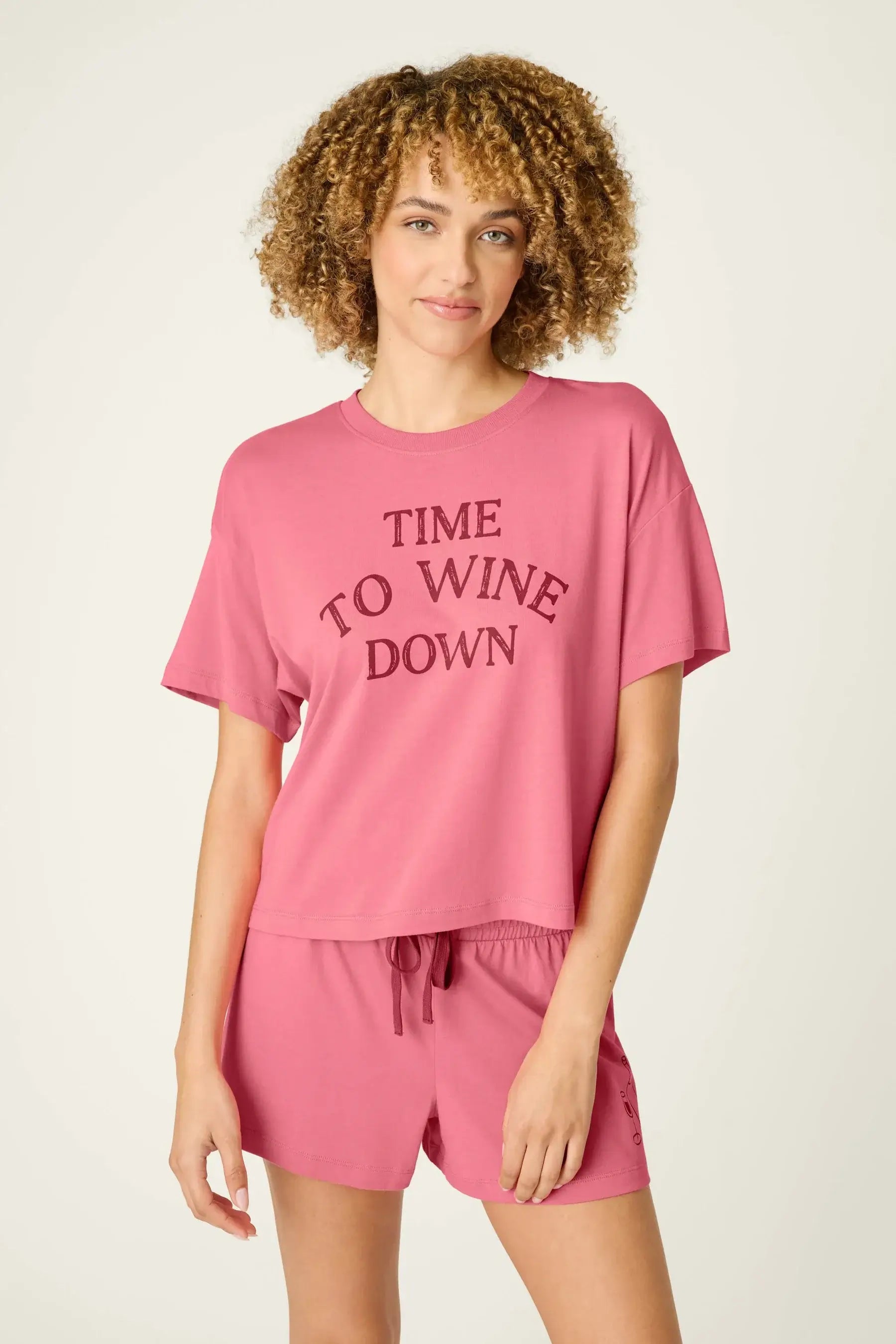 PJ SALVAGE Graphic Print Softee Tee & Short Lounge Set in "Time to Wine Down" rose pink. Model stands against a light background in a close-up shot