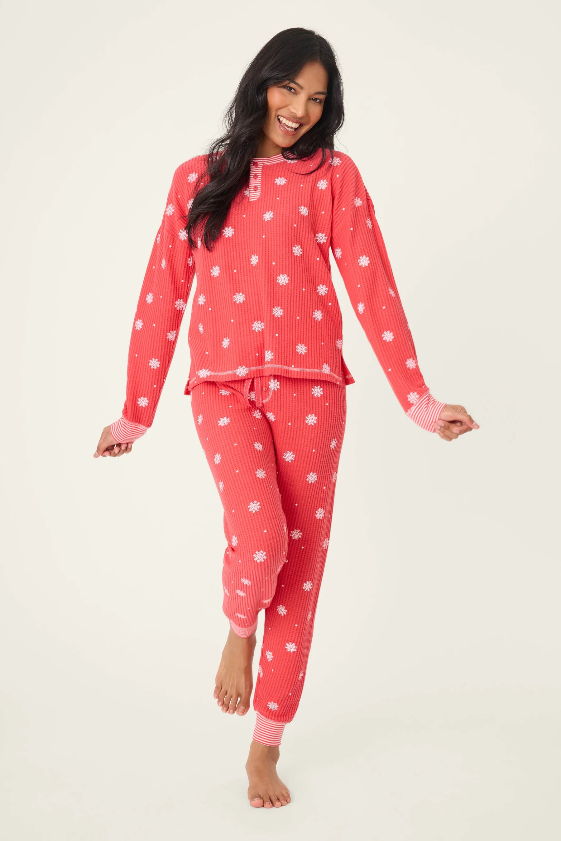 Woman wearing Ski Jammie Classics Brushed Thermal PJ Set, featuring playful winter prints in red and pink.