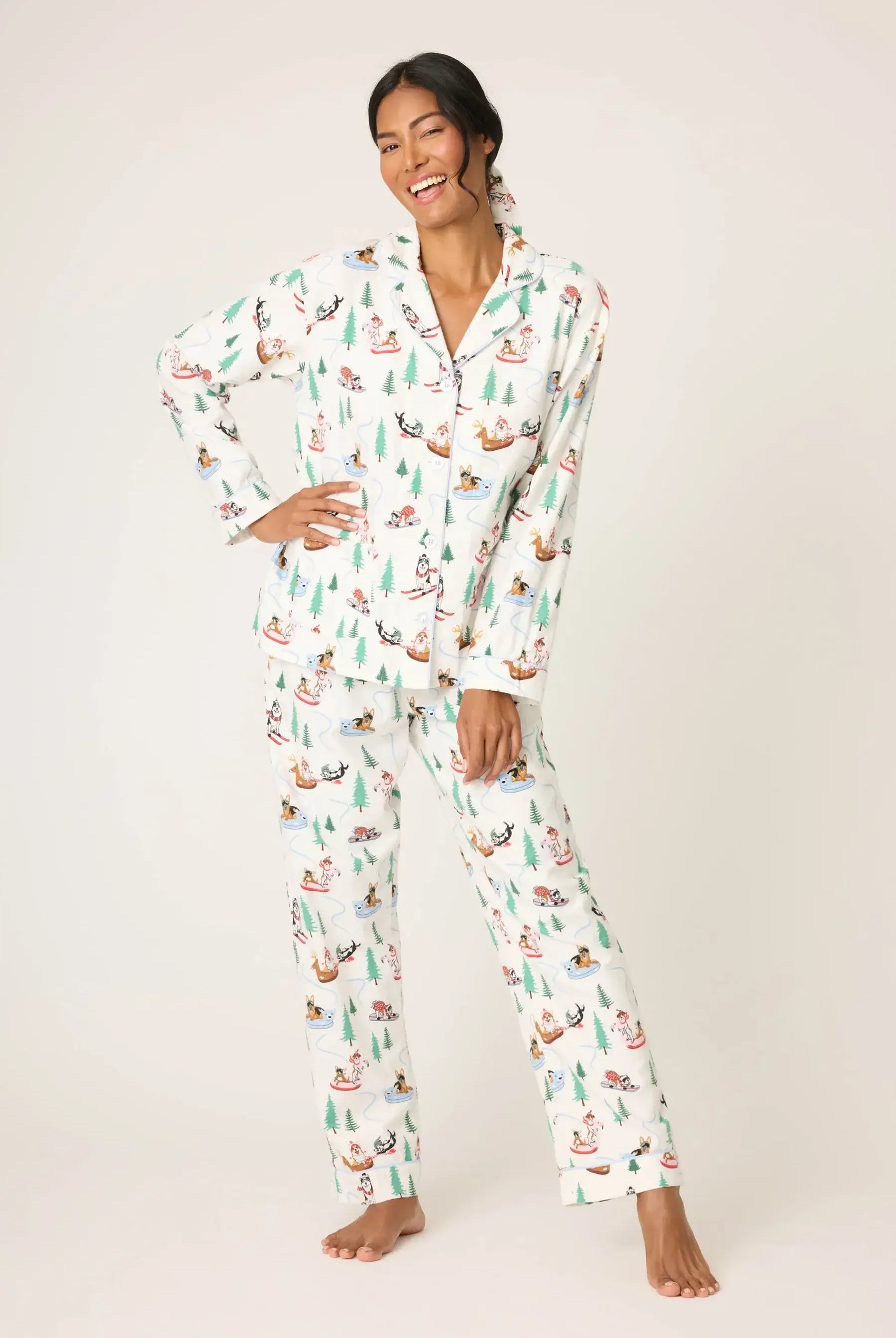 Model Candy wearing the PJ Salvage "Sleigh All Day" 3-Piece Flannel PJ Set in winter white with playful dogs skiing and sledding. She is wearing the button-front top, drawstring pants, and matching headband.