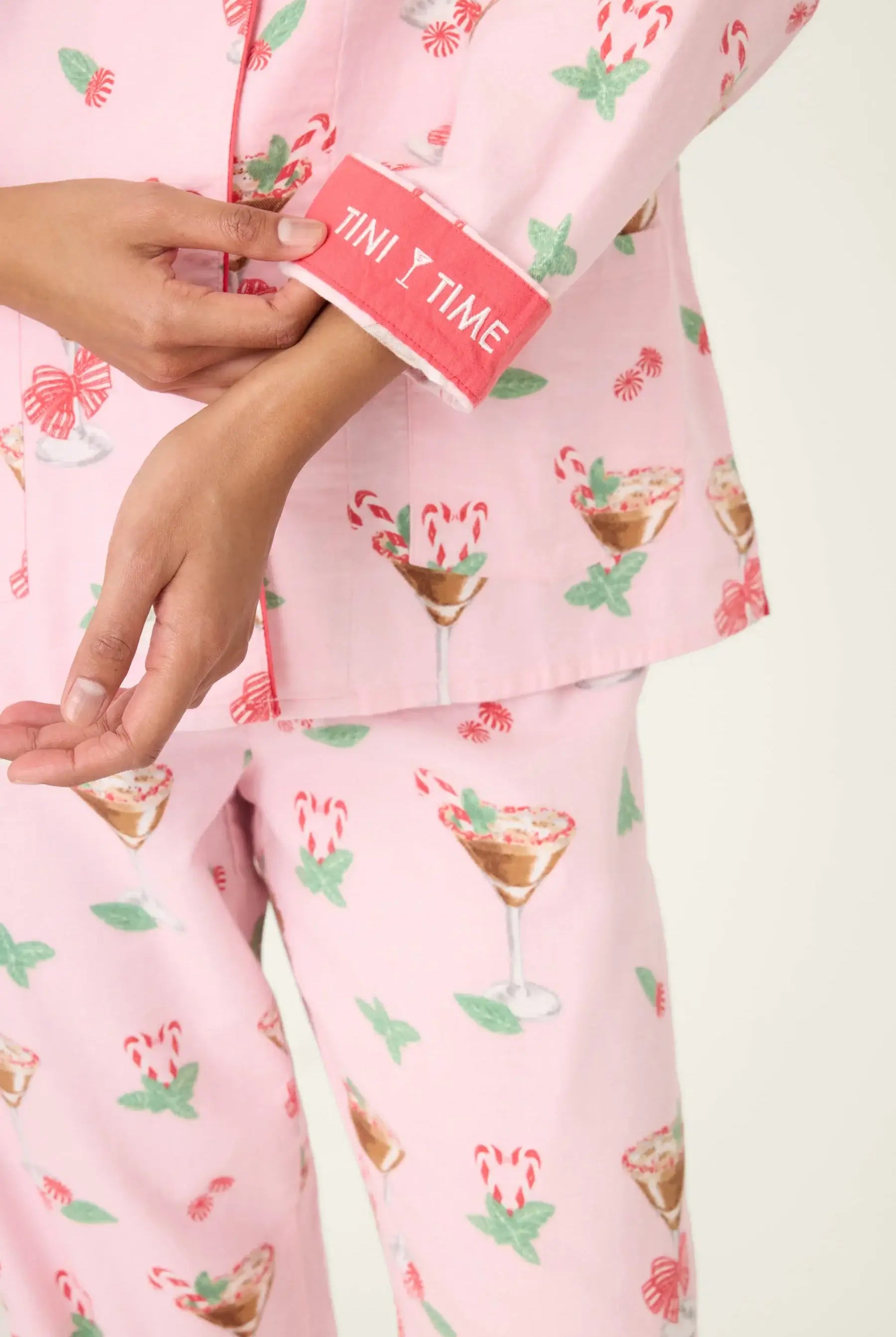 Close-up of the sleeve cuff on the pink flannel pyjama top, showing the contrast piping and the embroidered text "Tini Time".