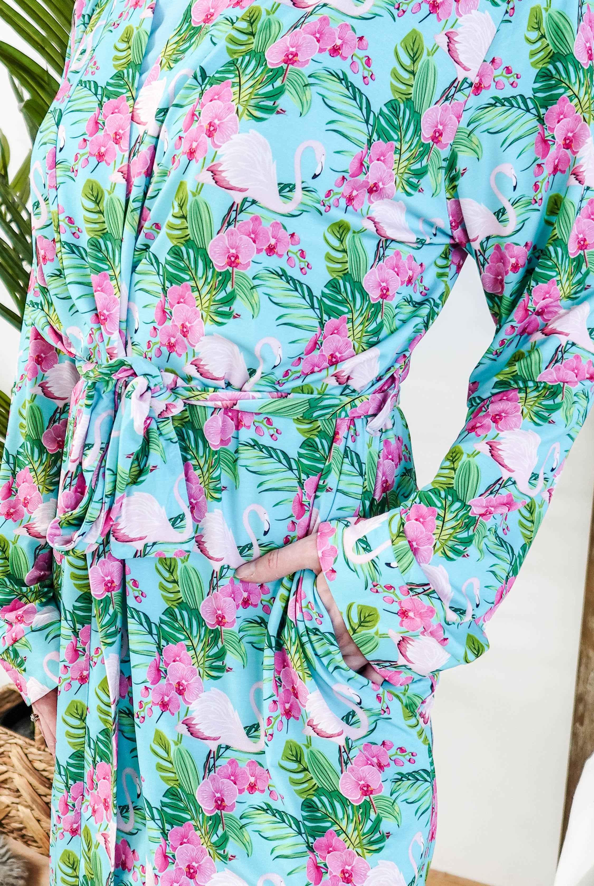 Tropic Like It's Hot Bamboo Short Robe | Georgia Rylan
close up of print of pink flamingos and orchids on a sky blue background and green tropical leaves