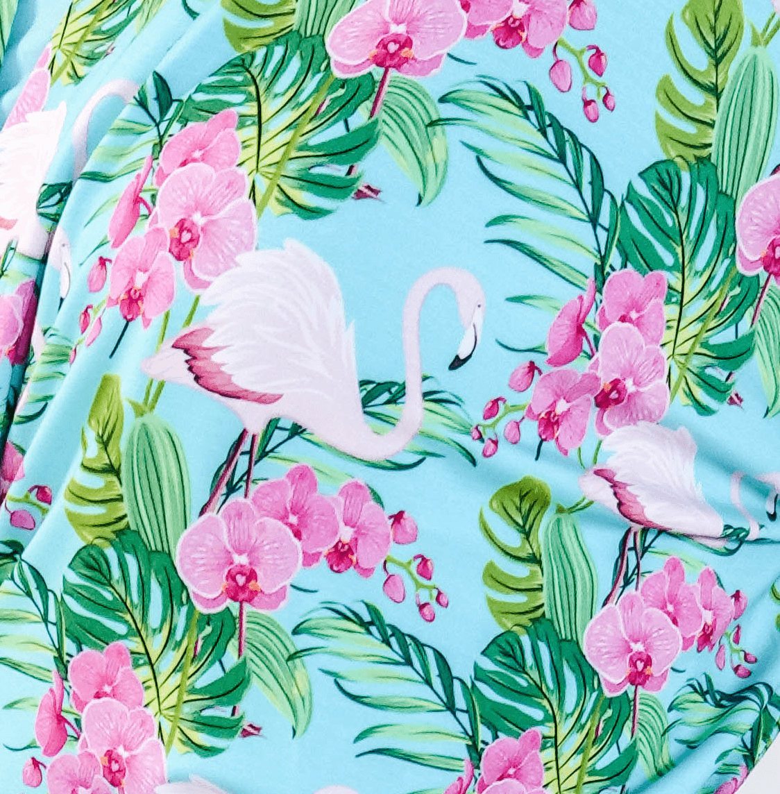 Tropic Like its Hot Print showing close up of fabric, texture and tropical flamingo and floral print on a light blue background