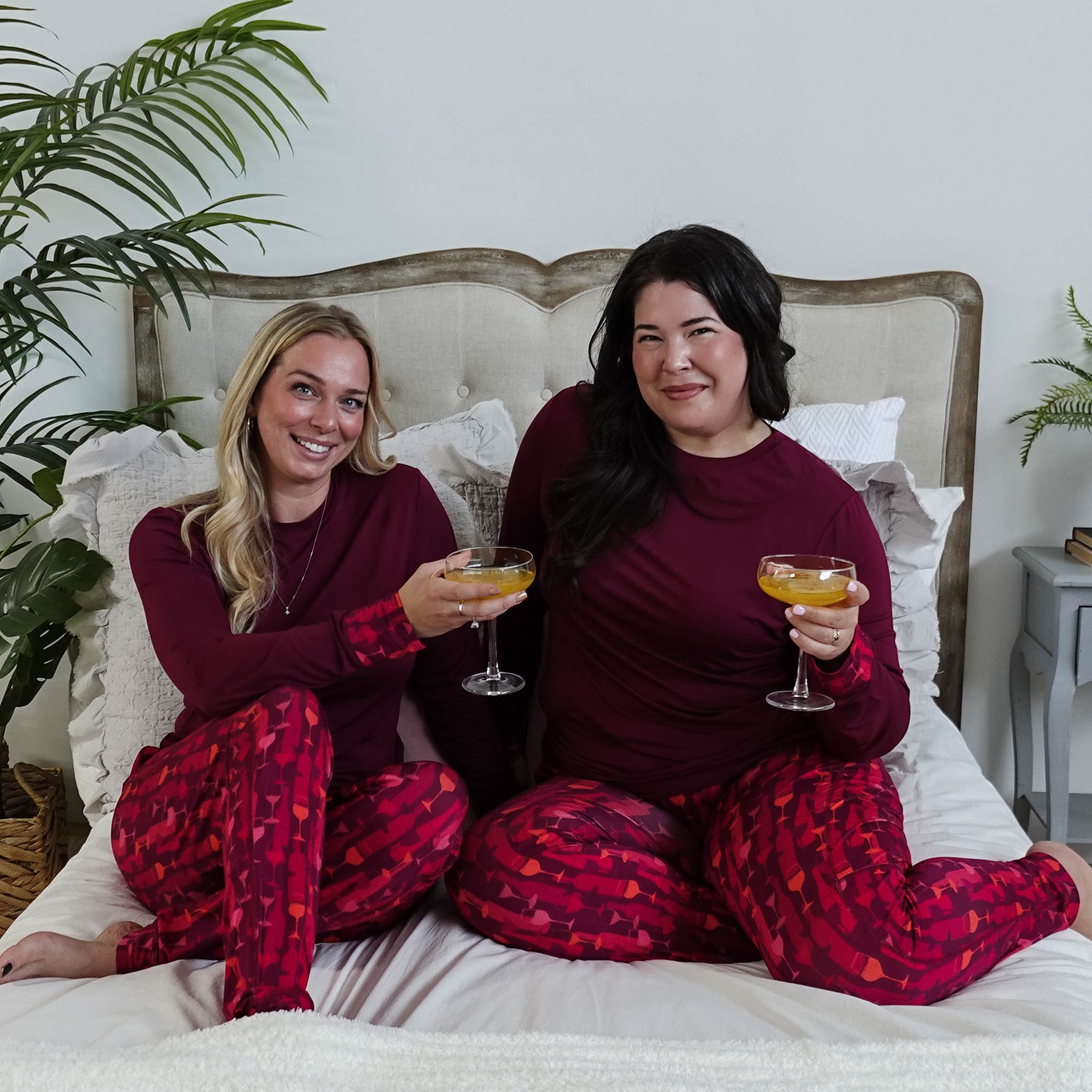 Vino Dreams PJ Long Sleeve Jogger Bamboo Set | GEORGIA RYLAN for women - two models cheers on a bed wearing the wine inspired set