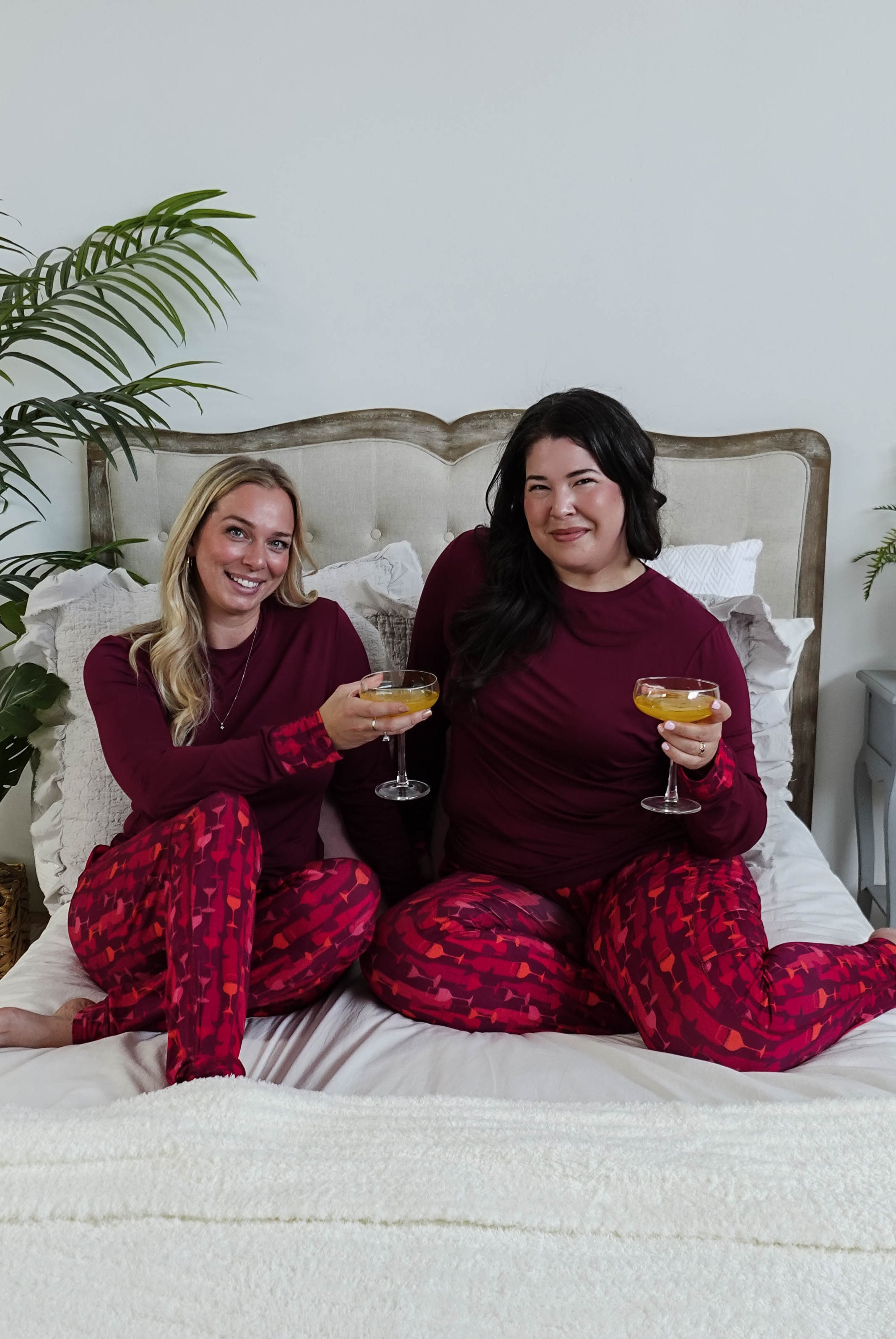 Vino Dreams PJ Long Sleeve Jogger Bamboo Set | GEORGIA RYLAN for women - two models cheers on a bed wearing the wine inspired set