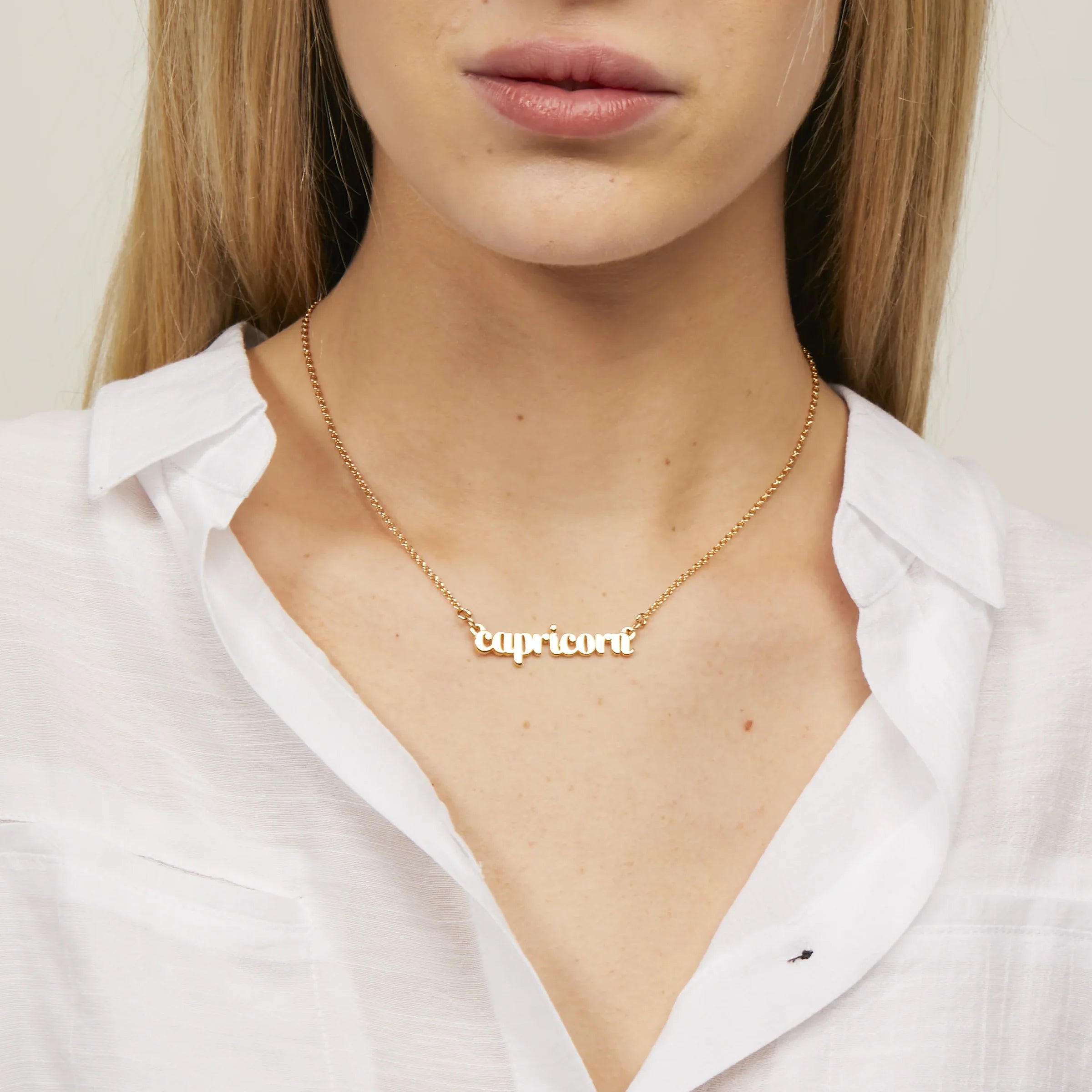 Zodiac Script Necklace in 14K Plated Gold featuring 'Capricorni' worn by a model.