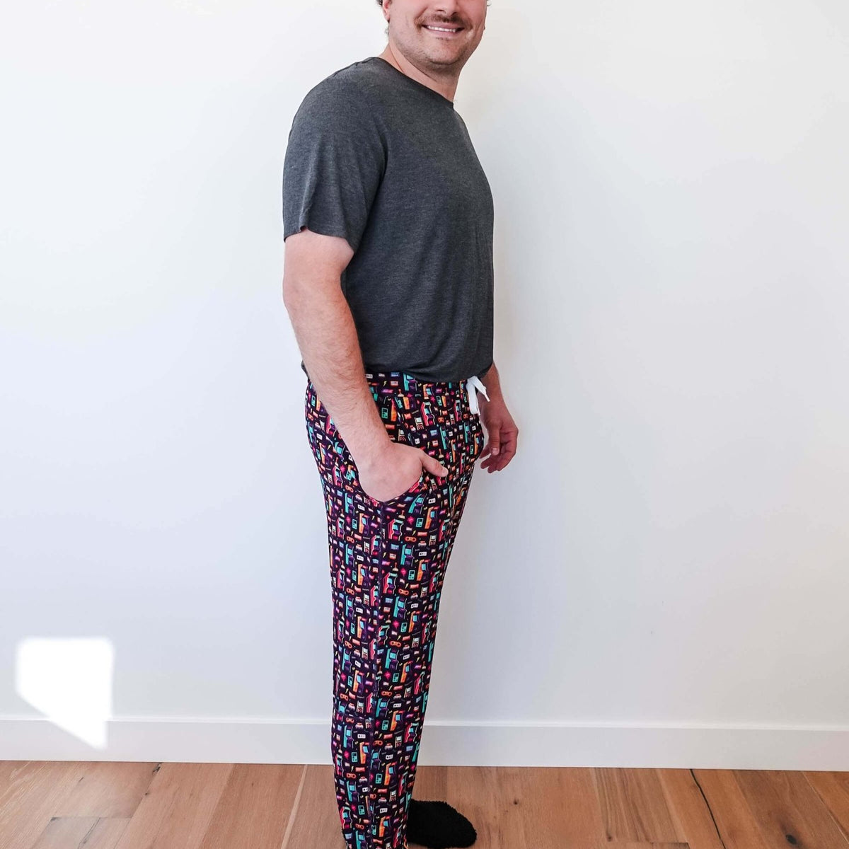 Man wearing Arcade After Dark Unisex Bamboo Jogger with graphic design, paired with a gray t-shirt, and socks.