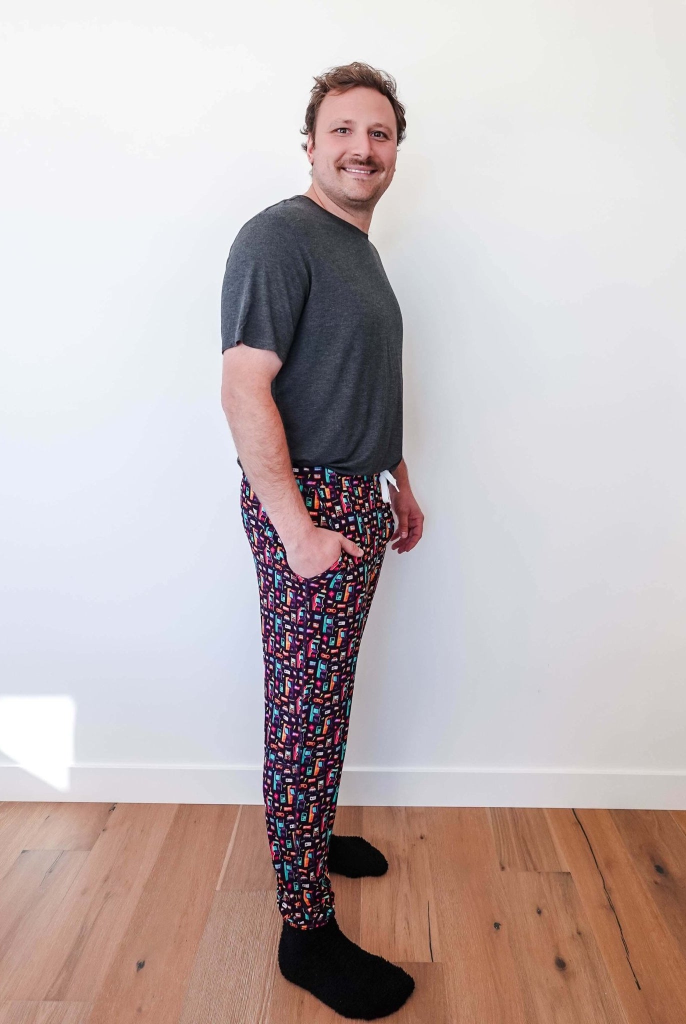 Man wearing Arcade After Dark Unisex Bamboo Jogger with graphic design, paired with a gray t-shirt, and socks.