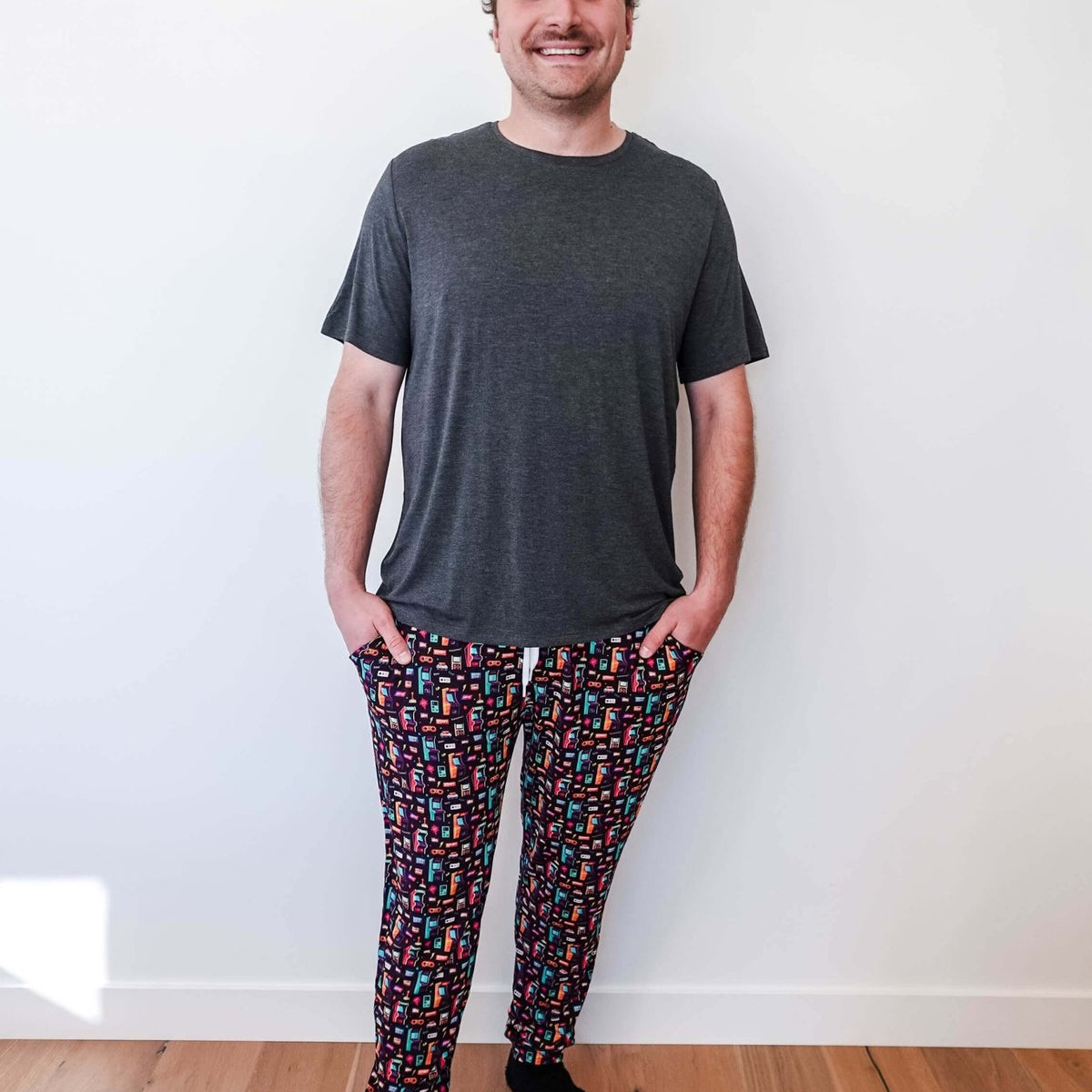 Man wearing Arcade After Dark Unisex Bamboo Jogger with graphic design, paired with a gray t-shirt, and socks.