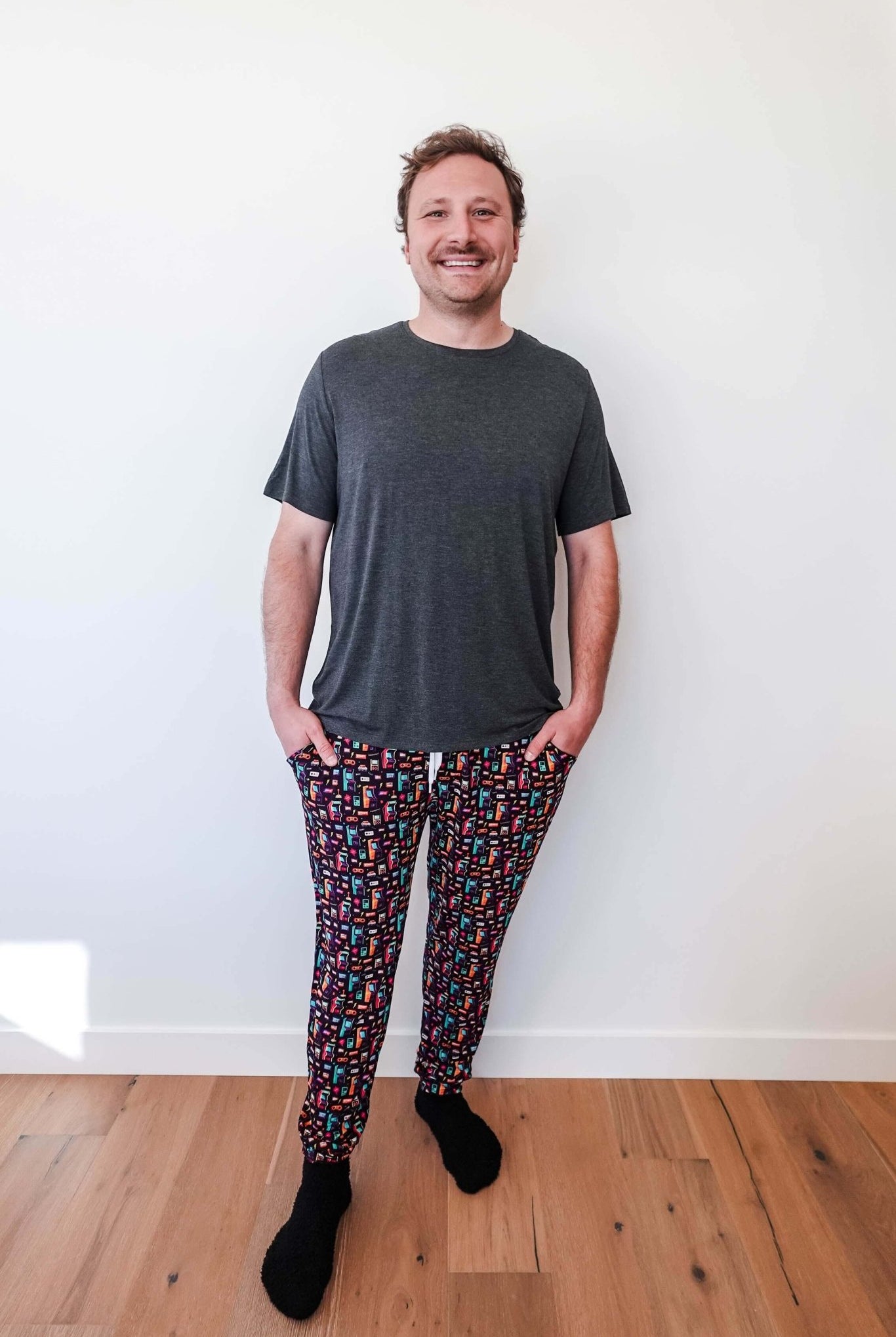 Man wearing Arcade After Dark Unisex Bamboo Jogger with graphic design, paired with a gray t-shirt, and socks.