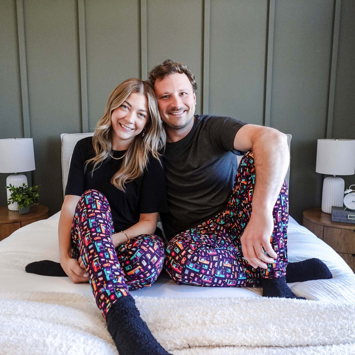Couple wearing Arcade After Dark Unisex Bamboo Jogger on a bed, showcasing a fun and cozy loungewear style.