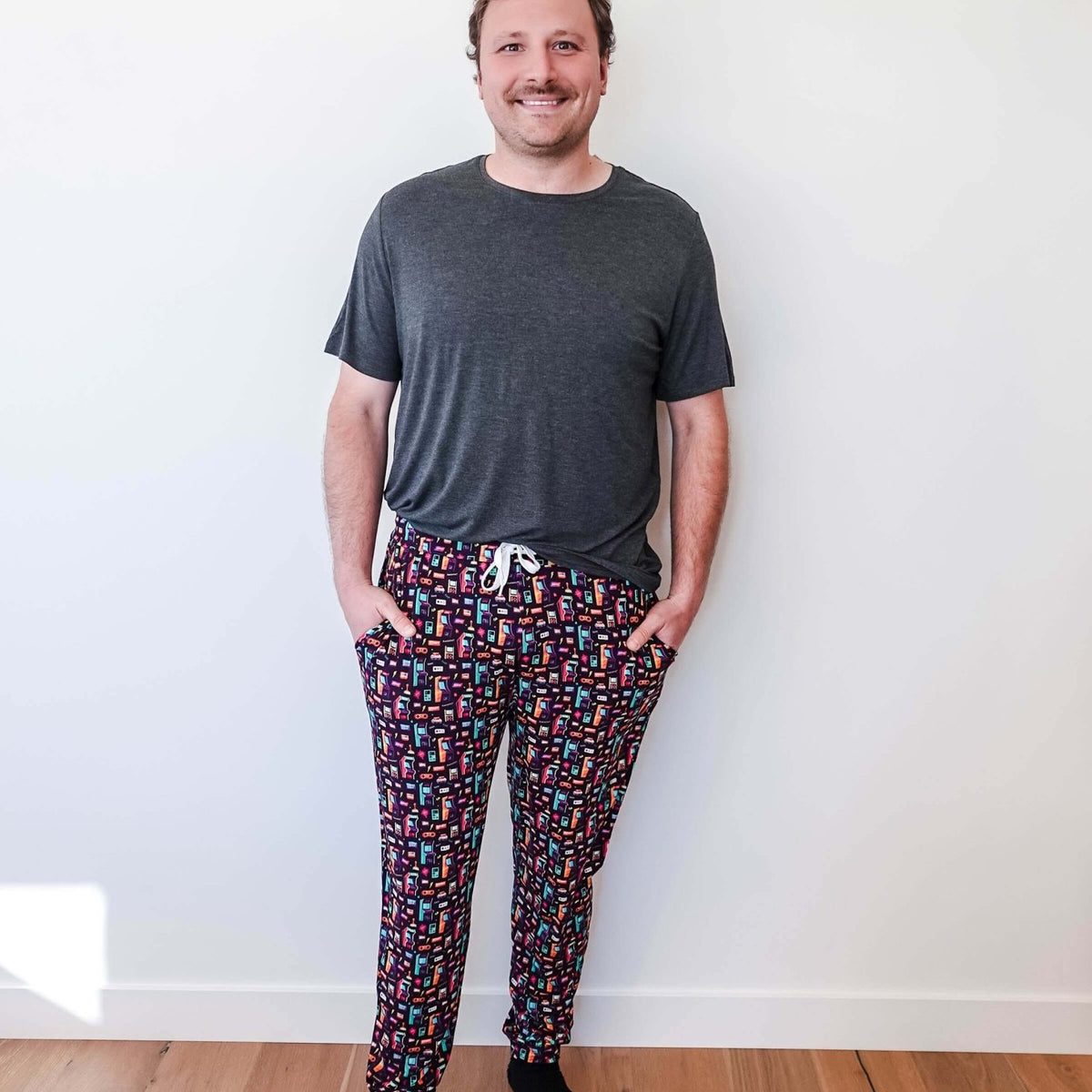Man wearing Arcade After Dark Unisex Bamboo Jogger with graphic design, paired with a gray t-shirt, and socks.