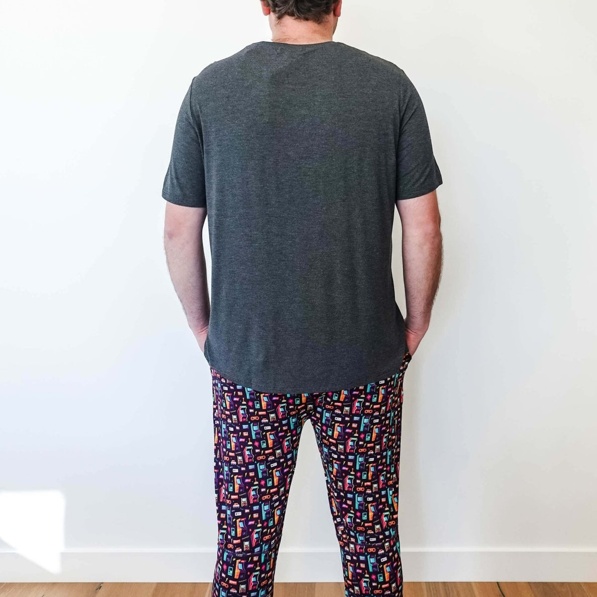 Man wearing Arcade After Dark Unisex Bamboo Jogger with graphic design, paired with a gray t-shirt, and socks.