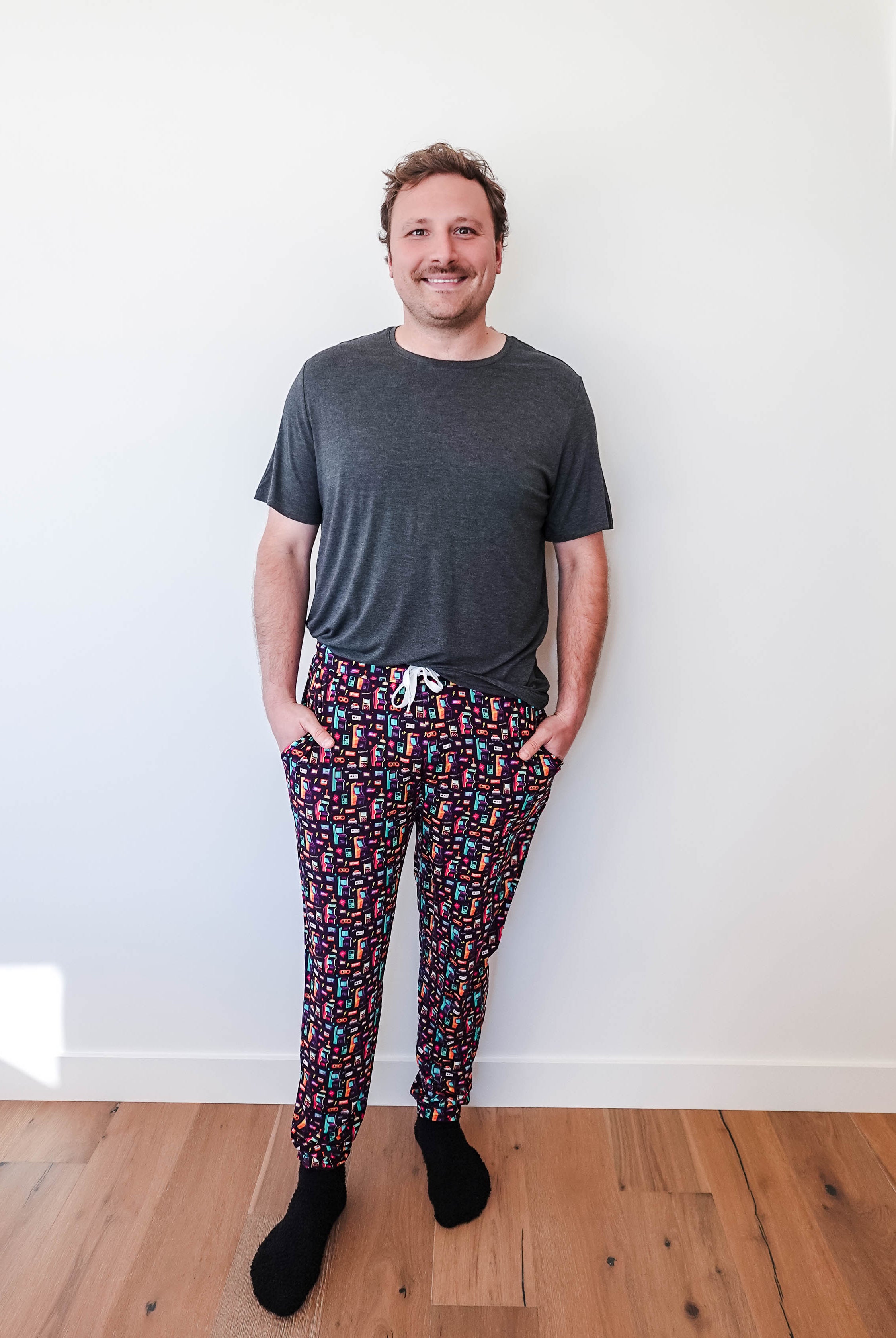 Man wearing Arcade After Dark Unisex Bamboo Jogger with graphic design, paired with a gray t-shirt, and socks.