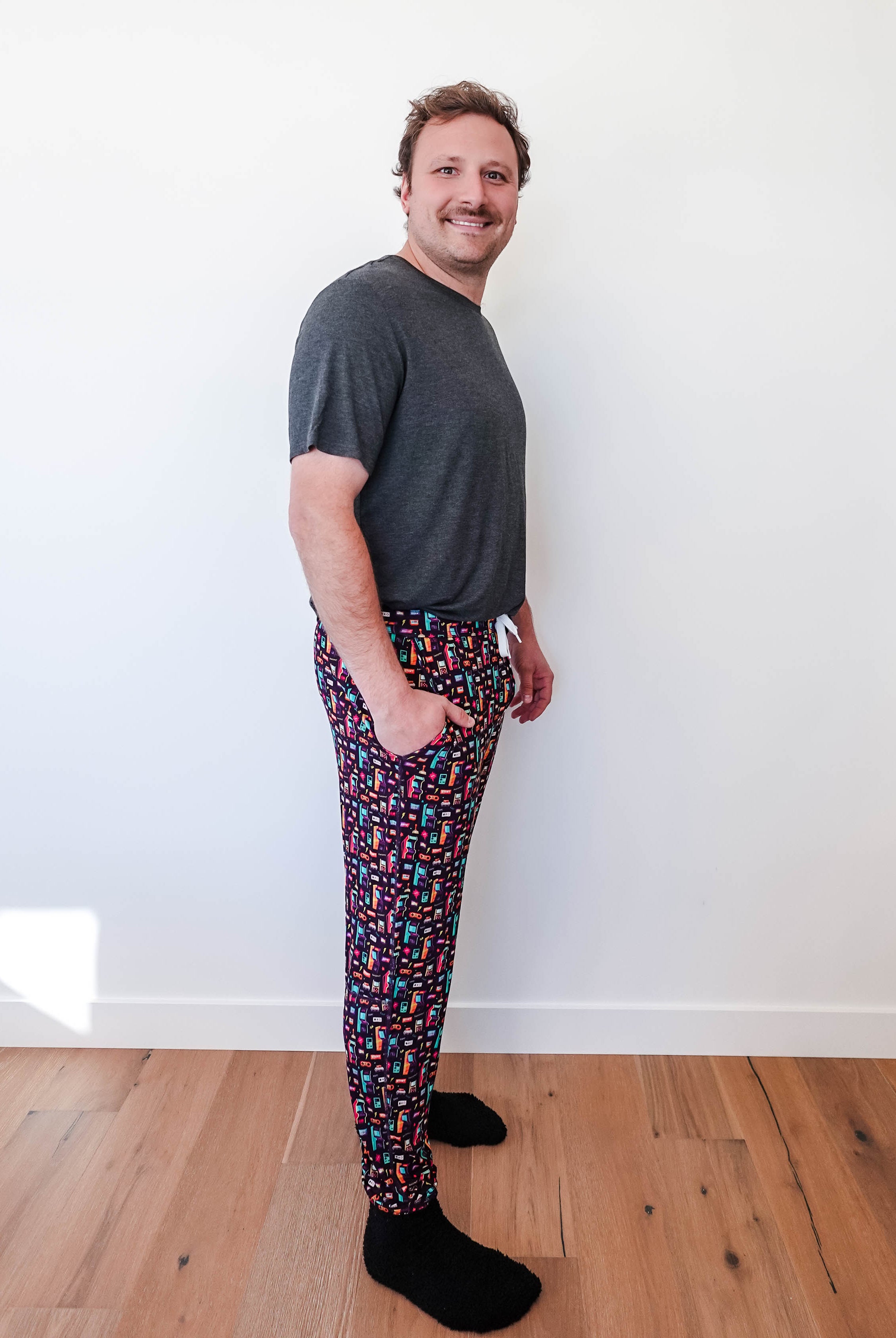 Man wearing Arcade After Dark Unisex Bamboo Jogger with graphic design, paired with a gray t-shirt, and socks.