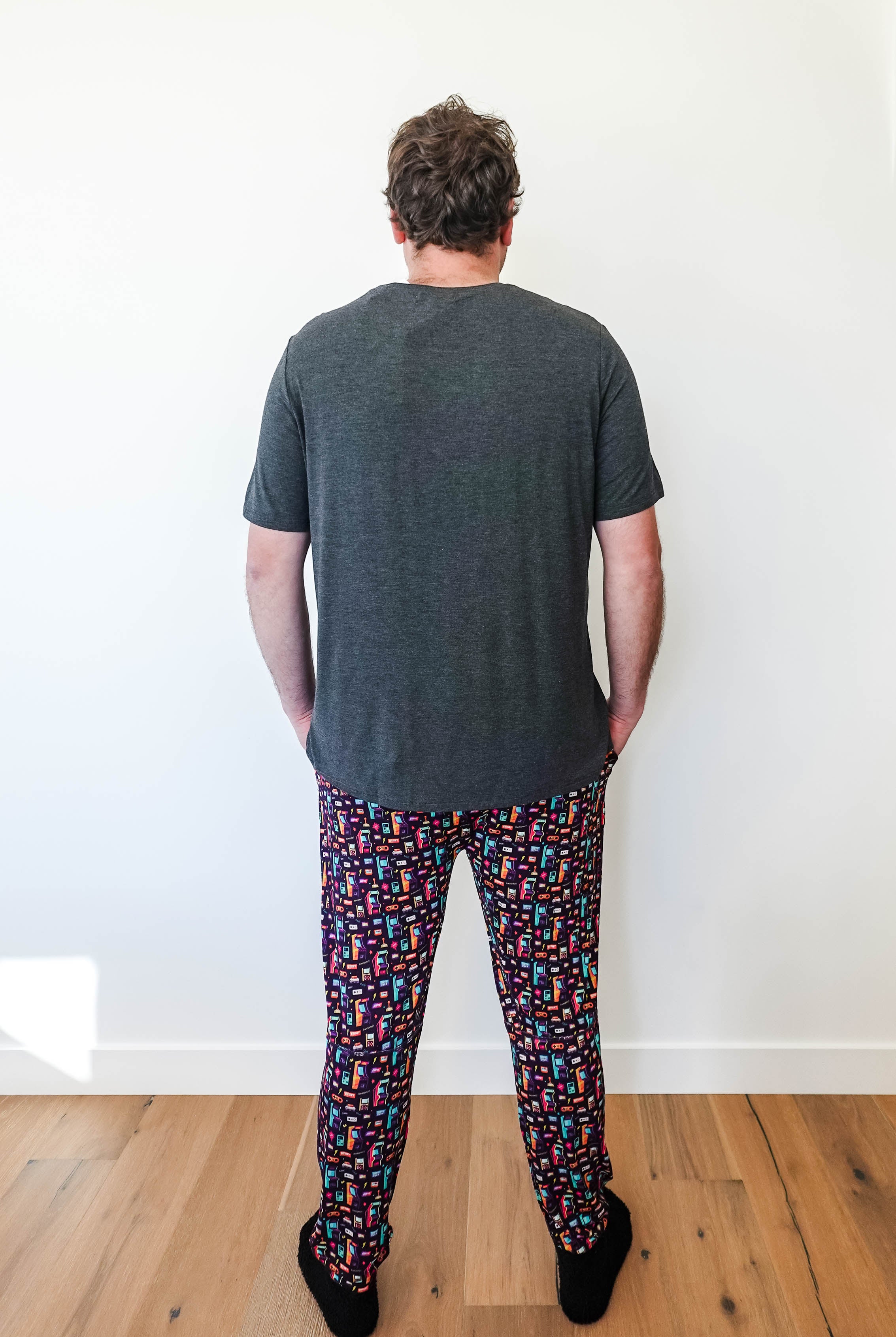 Man wearing Arcade After Dark Unisex Bamboo Jogger with graphic design, paired with a gray t-shirt, and socks.