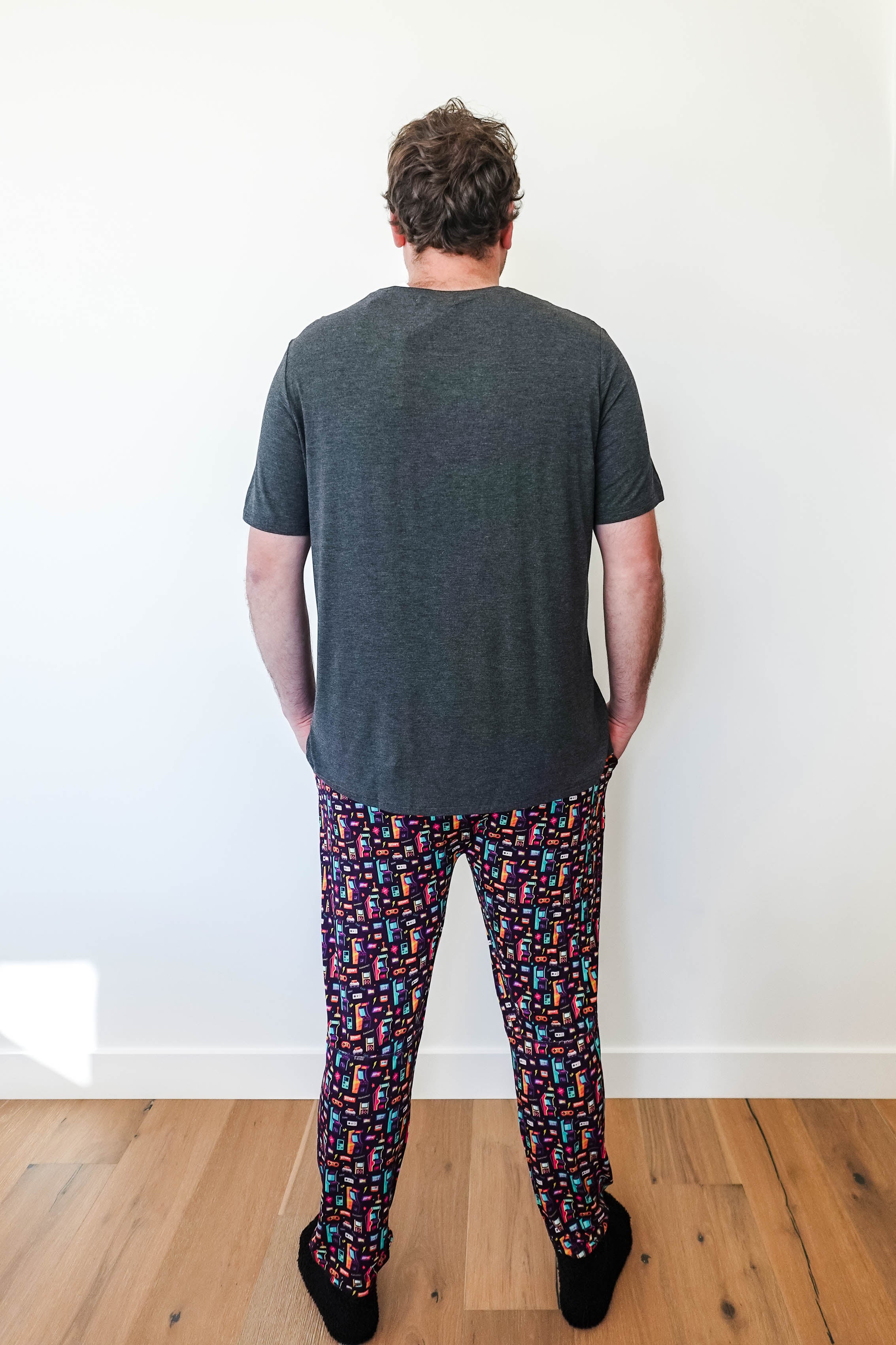 Man wearing Arcade After Dark Unisex Bamboo Jogger with graphic design, paired with a gray t-shirt, and socks.