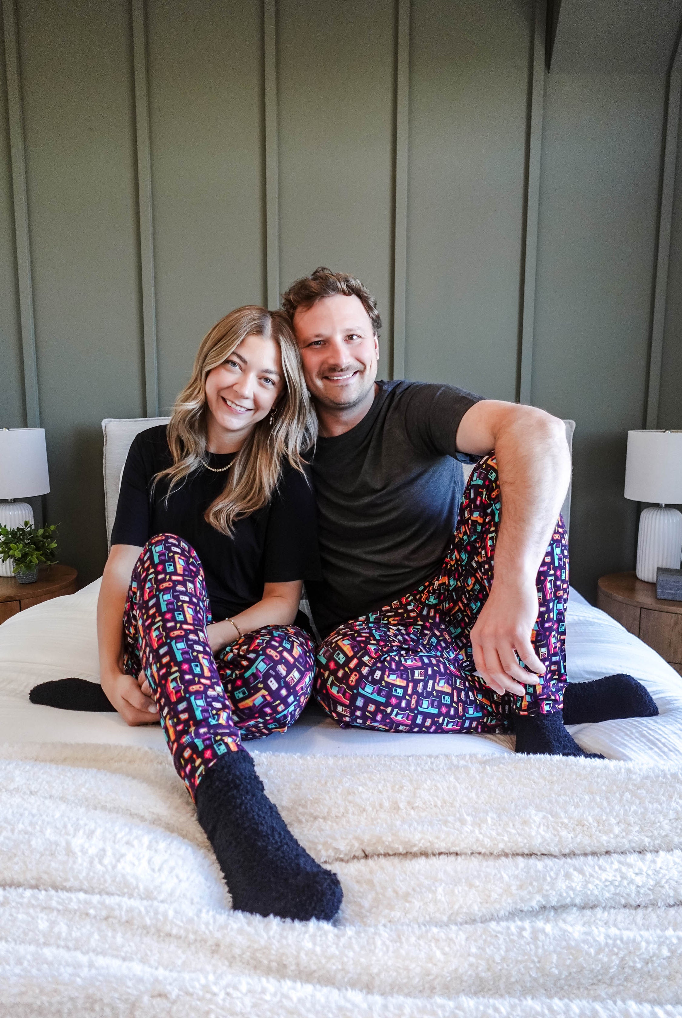 Couple wearing Arcade After Dark Unisex Bamboo Jogger on a bed, showcasing a fun and cozy loungewear style.