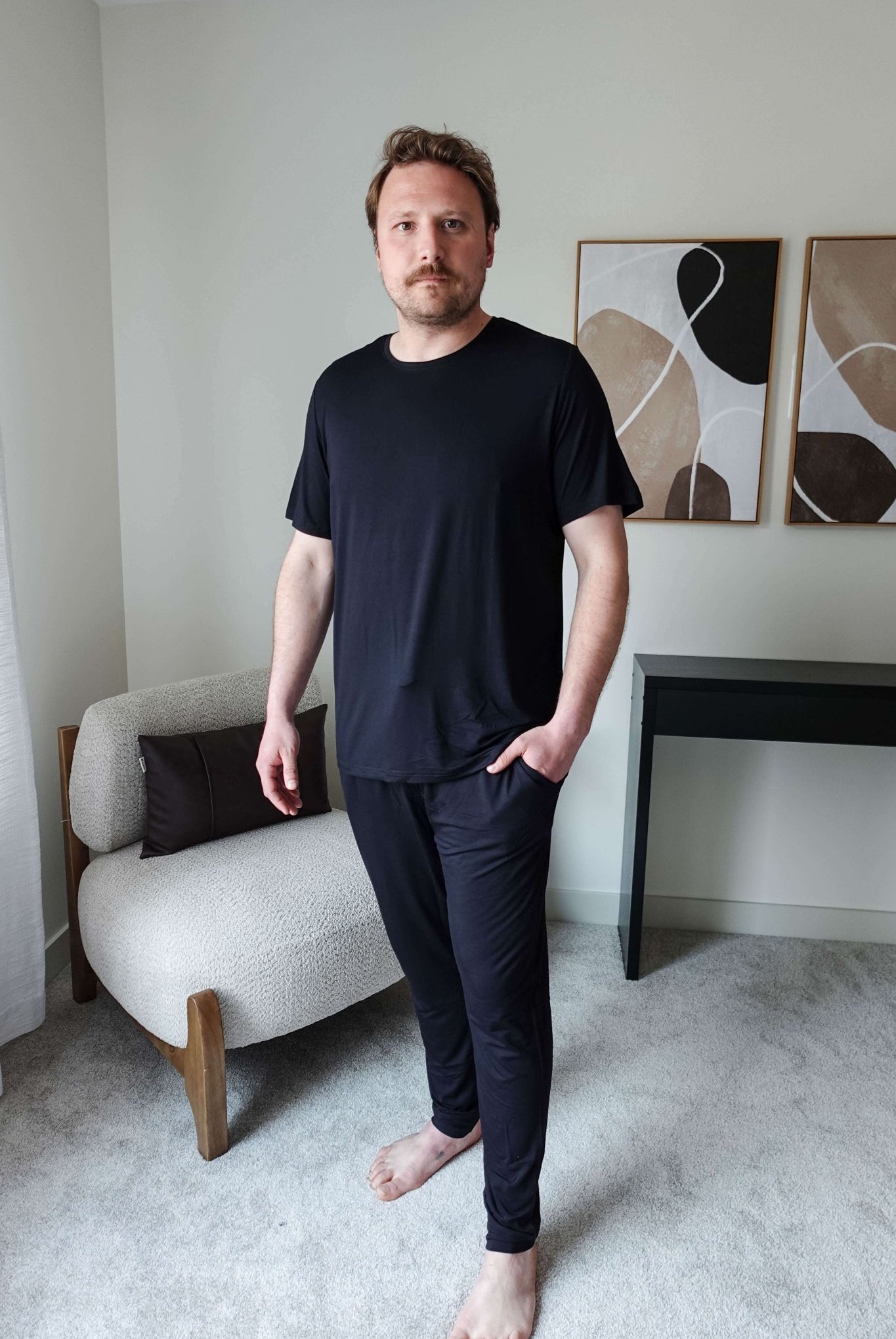 Black Unisex Short Sleeve Tee Bamboo showcased on a model standing in a modern interior setting.