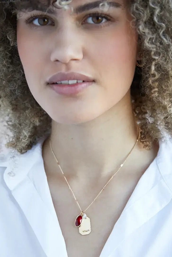 Birthstone Charm Necklace in 14k Plated Gold featuring a ruby stone, labeled 'Vitality', by Foxy Originals. Birthstone Charm Necklace in 14k Plated Gold for JUNE featuring a ruby stone, labeled 'Vitality', by Foxy Originals.