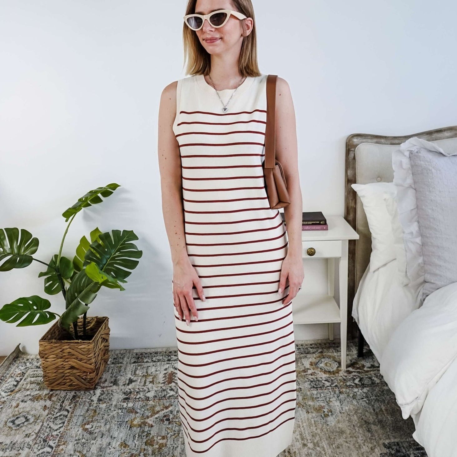 Woman wearing a brown and white striped knit dress in a bedroom setting.