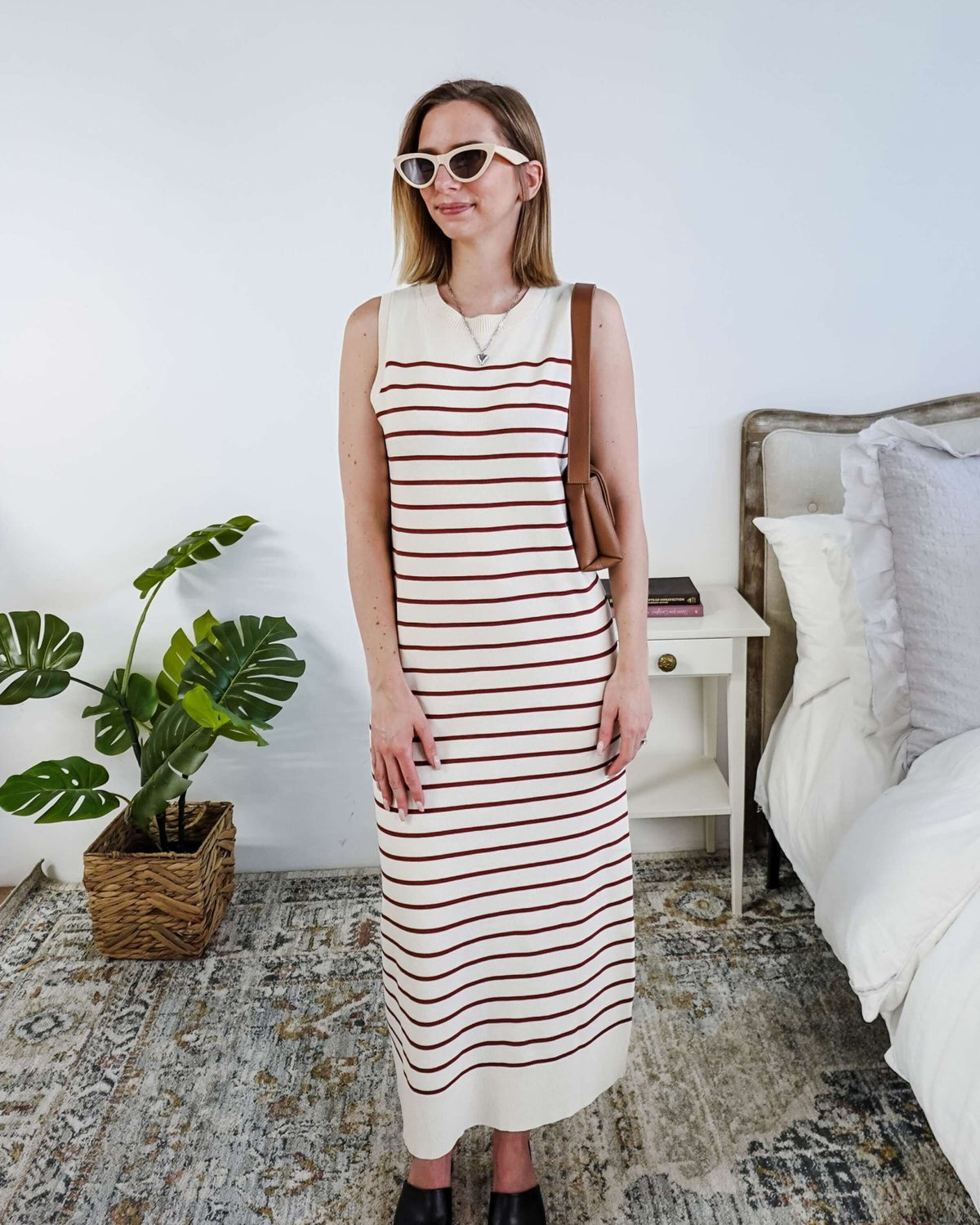 Woman wearing a brown and white striped knit dress in a bedroom setting.