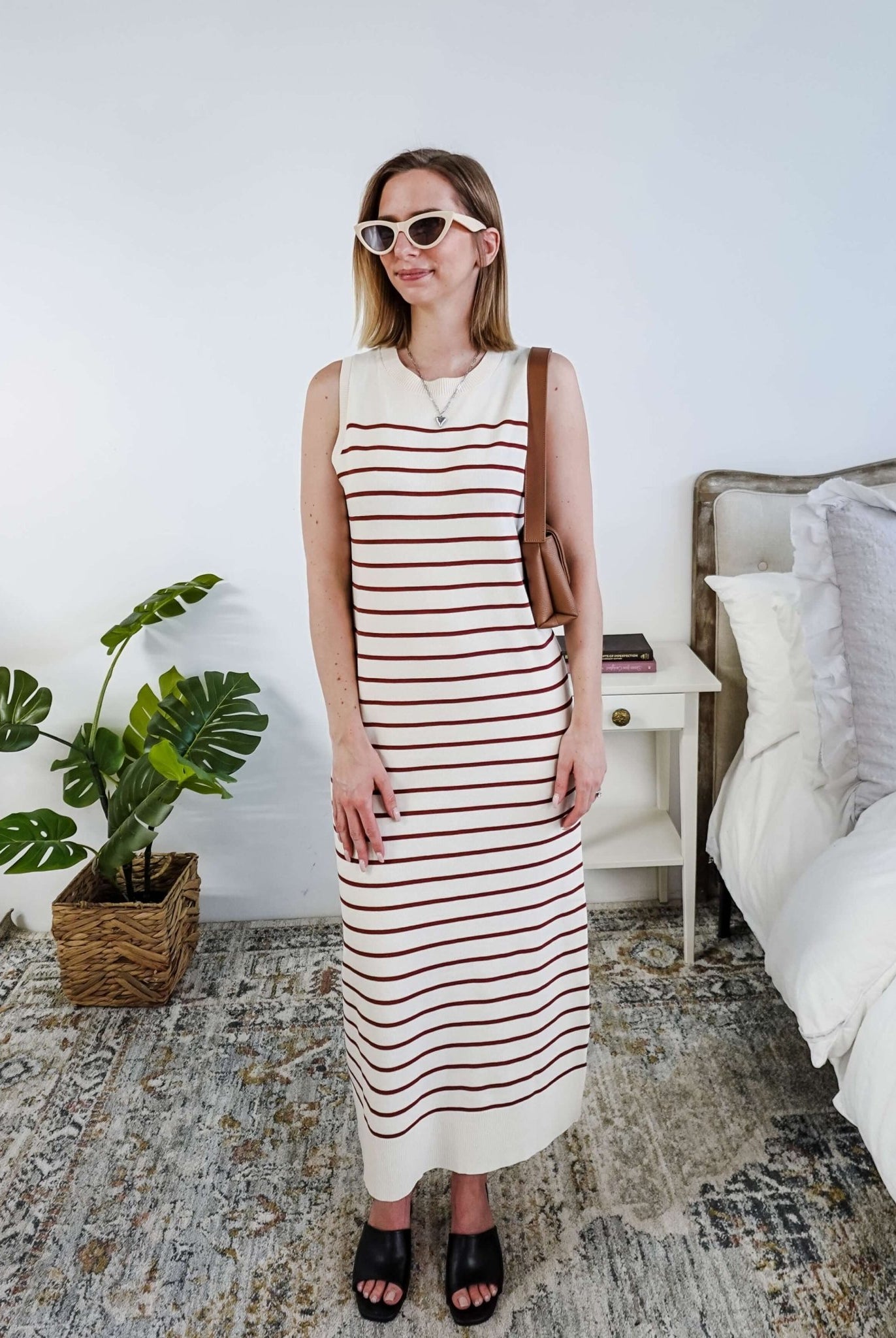 Woman wearing a brown and white striped knit dress in a bedroom setting.