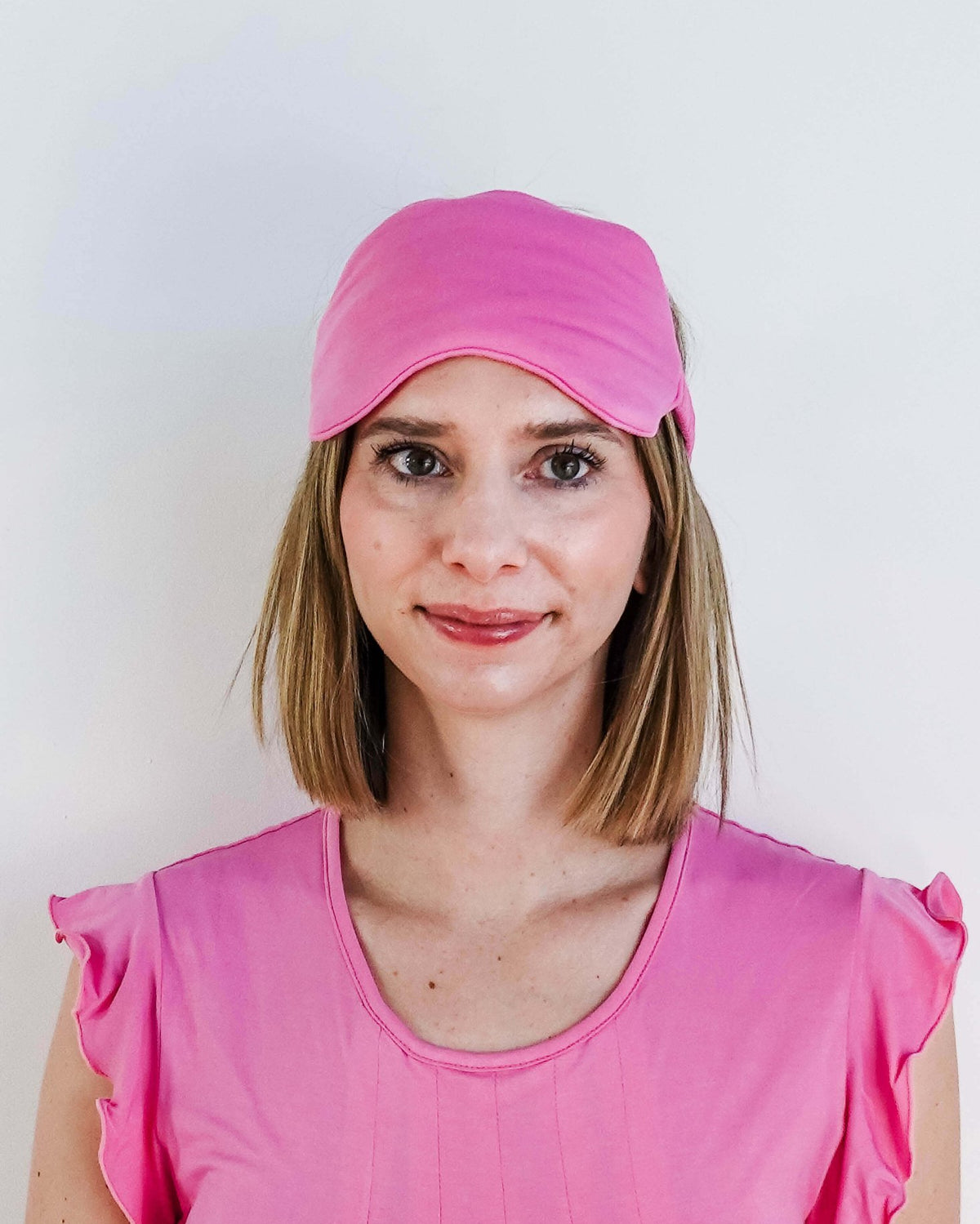 Bubblegum Pink Bamboo Sleep Eye Mask worn by a woman in pink top for comfortable sleep.