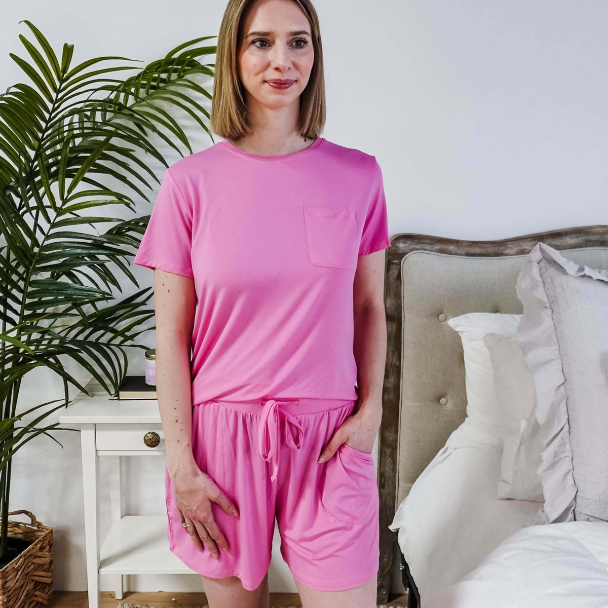 Woman wearing Bubblegum Pink Tee Short Bamboo Pajama Set, relaxed at home with a cozy bedroom background.