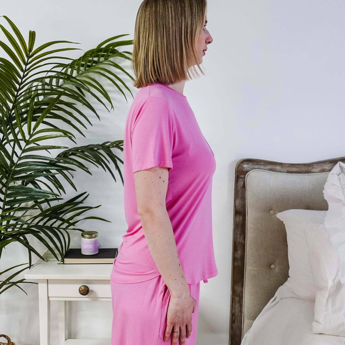 Bubblegum Pink Tee Short Bamboo Pajama Set worn by a woman standing in profile in a cozy bedroom.